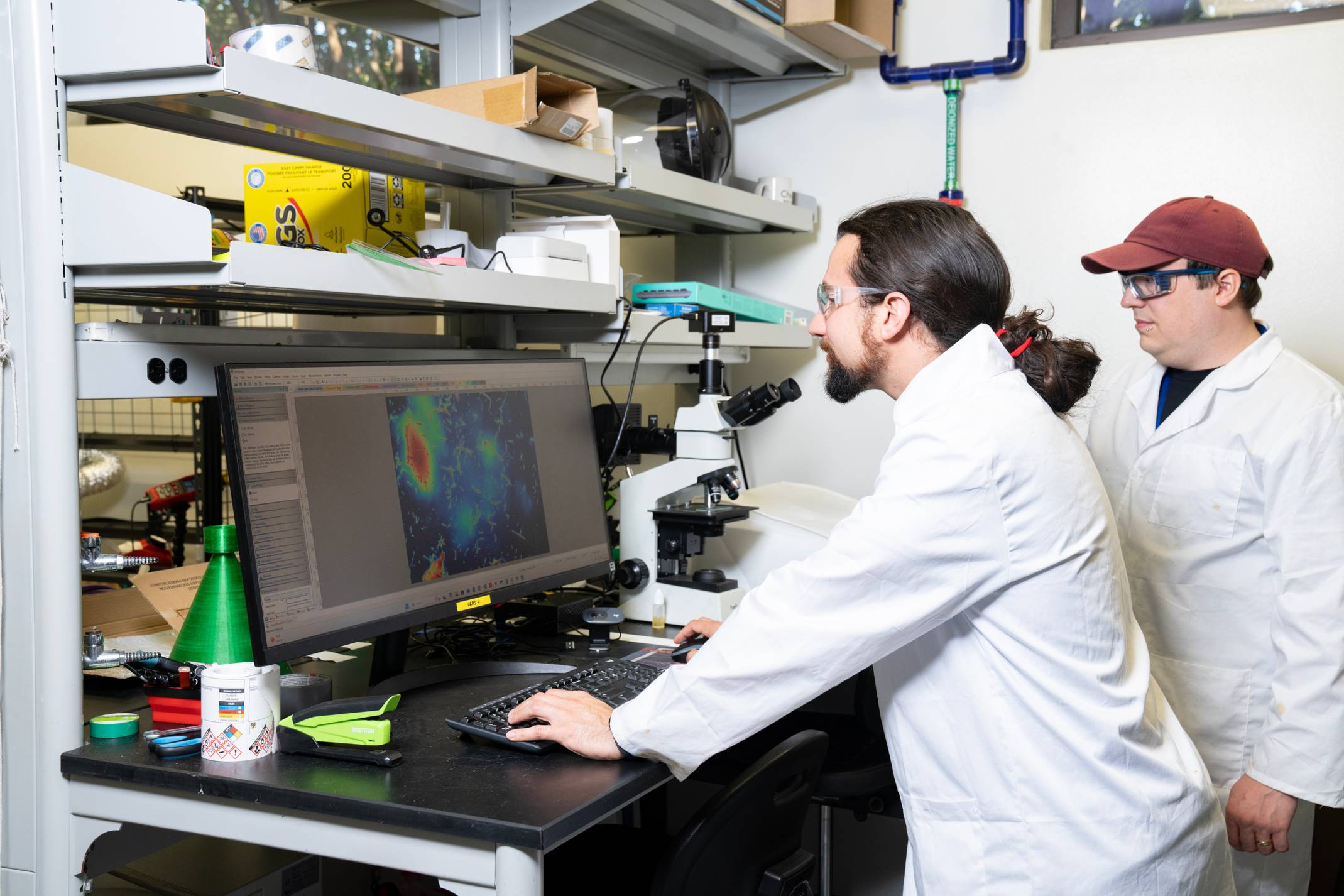 two men in white lab coats looking at computer