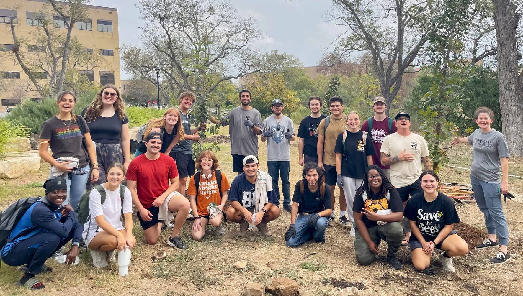 Young men and women pose for a group photo on grass