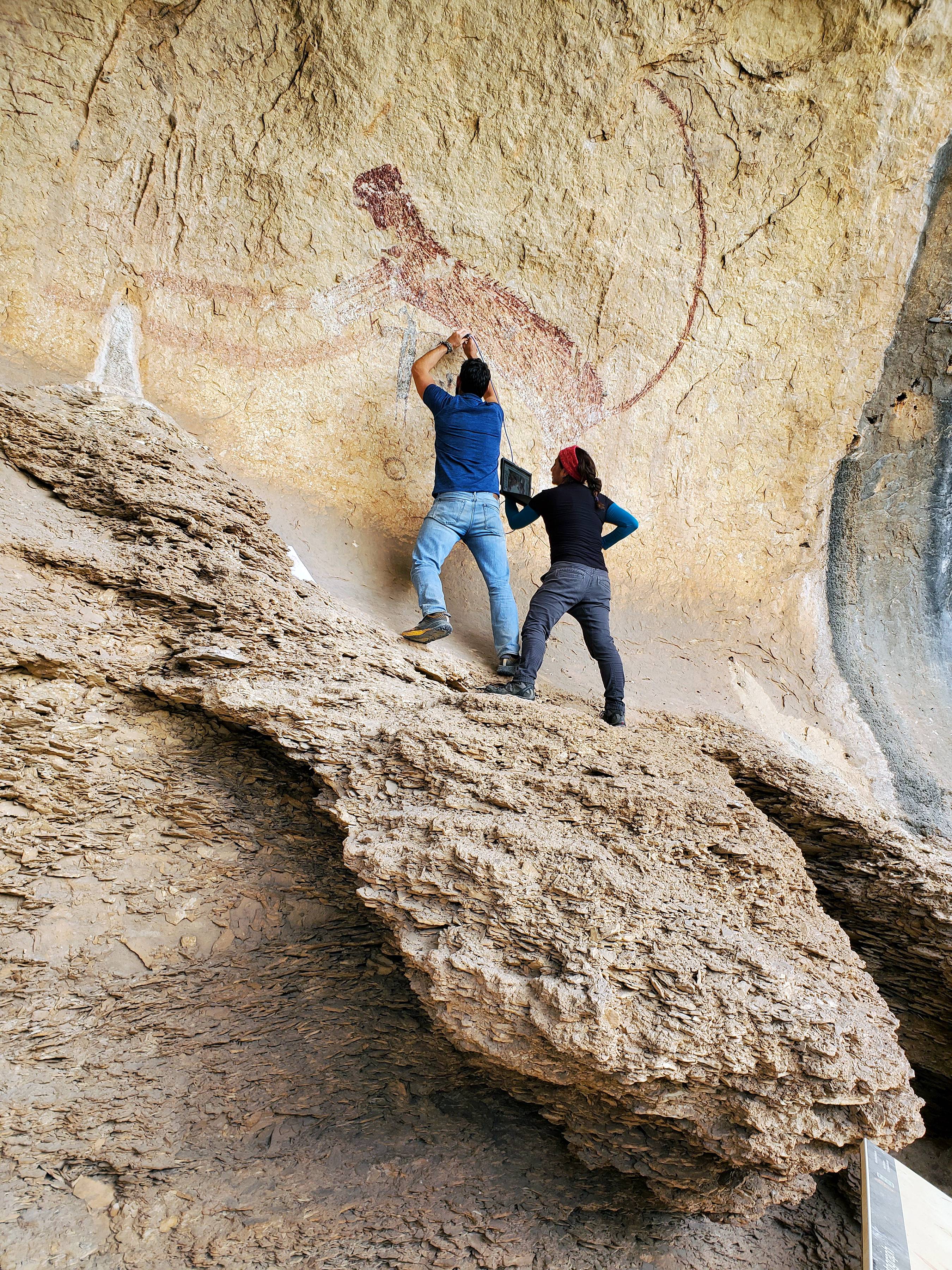 man and woman looking at ancient rock art on pecos river rock