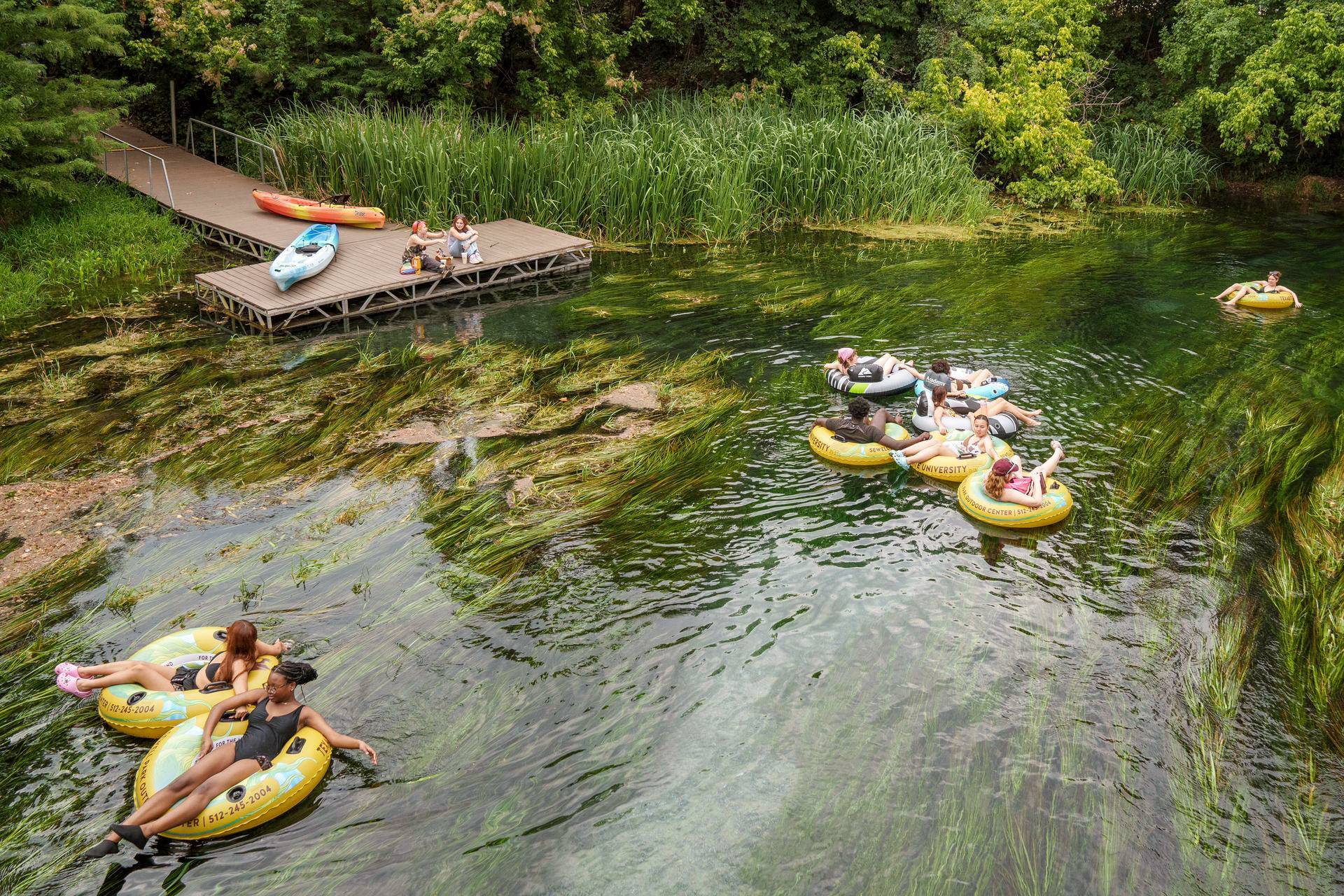 Students float down the San Marcos River at Sewell Park on the Texas State campus.