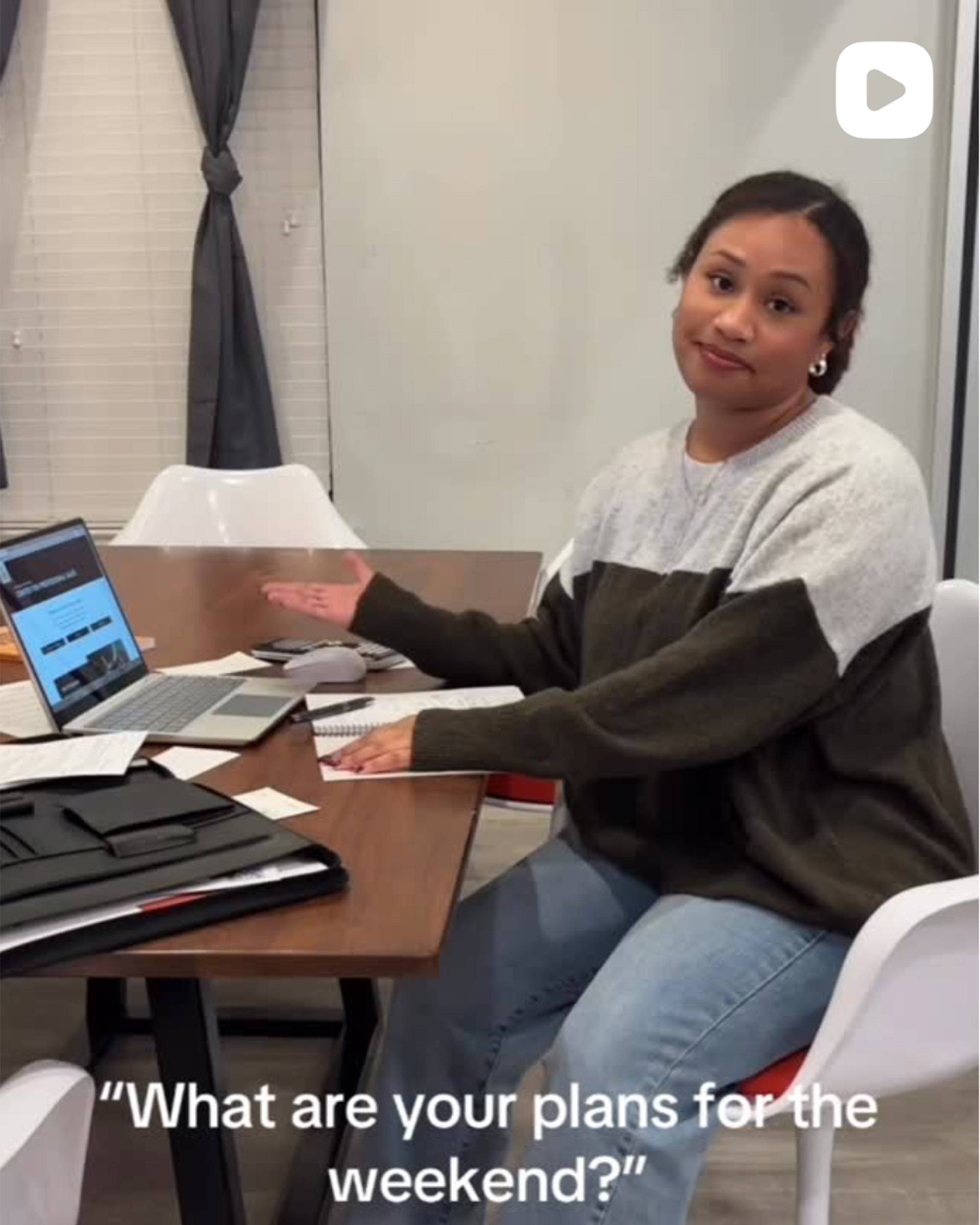 Young woman seated at a table, shrugging