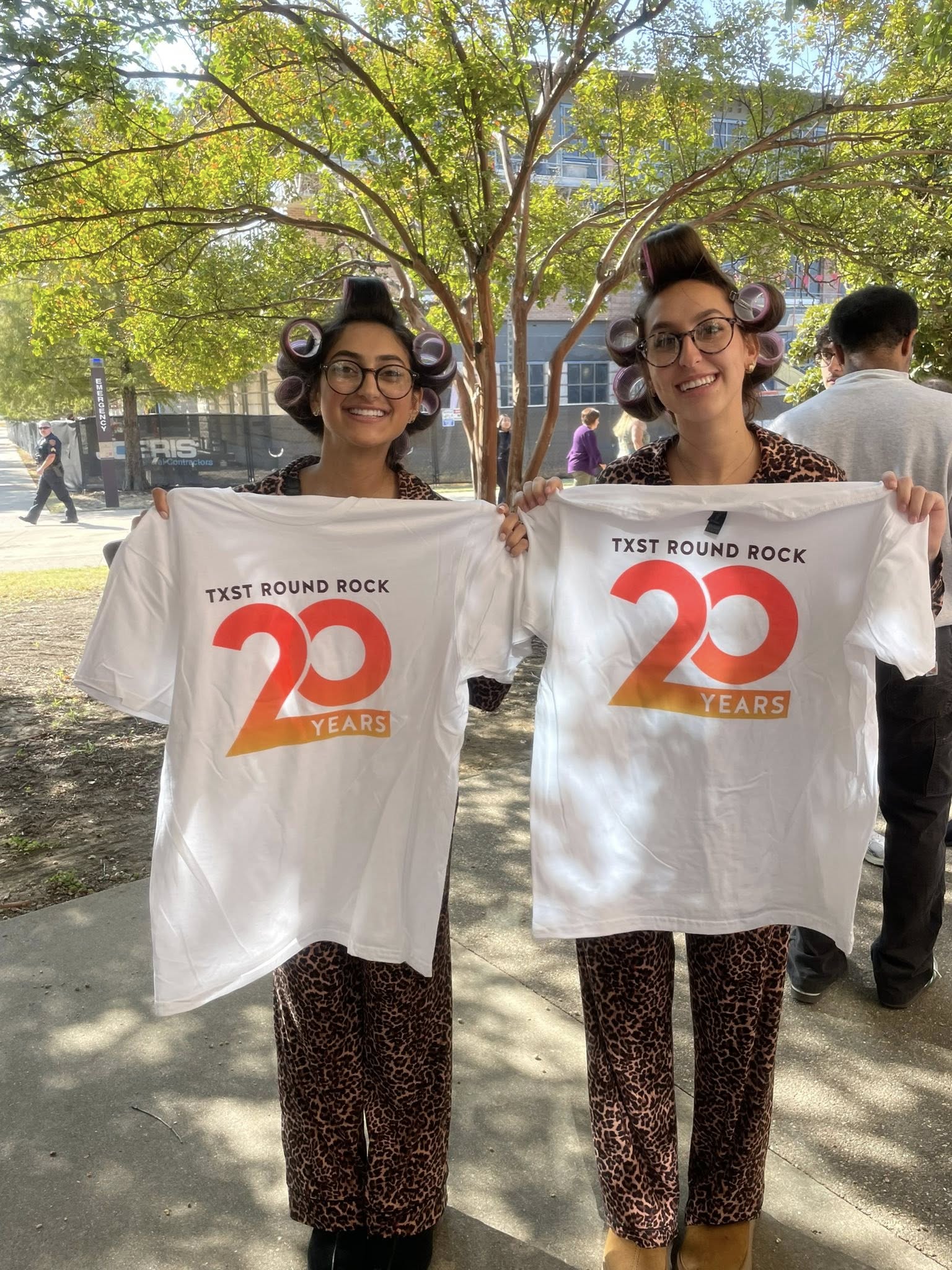 two students holding 20th logo tshirts
