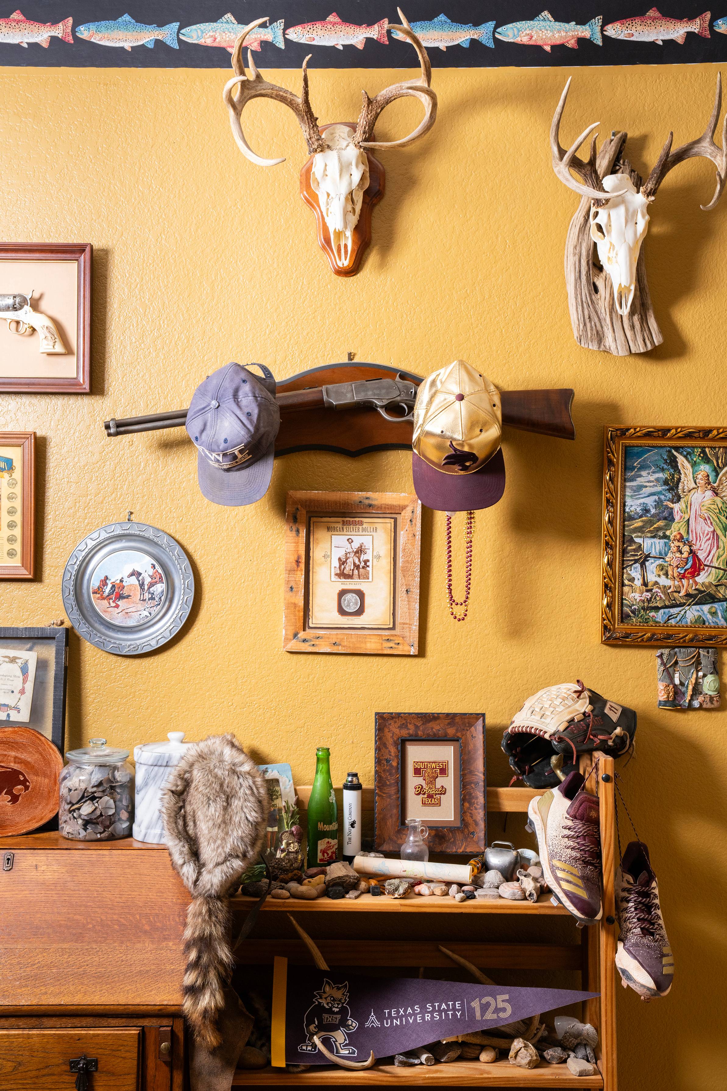 Texas State University and hunting memorabilia are hung on a yellow wall.