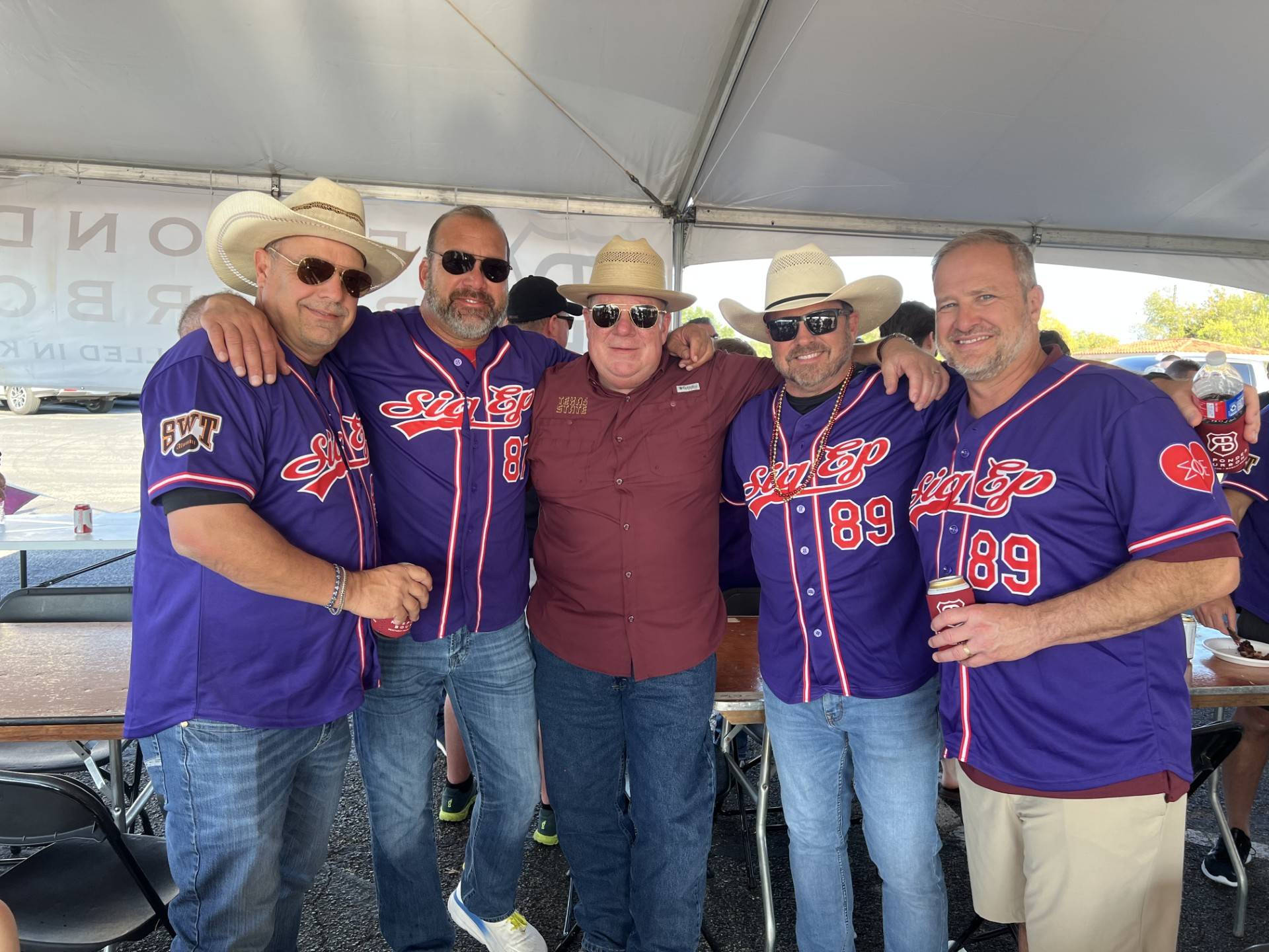 Men posing with eachother at a tailgate 