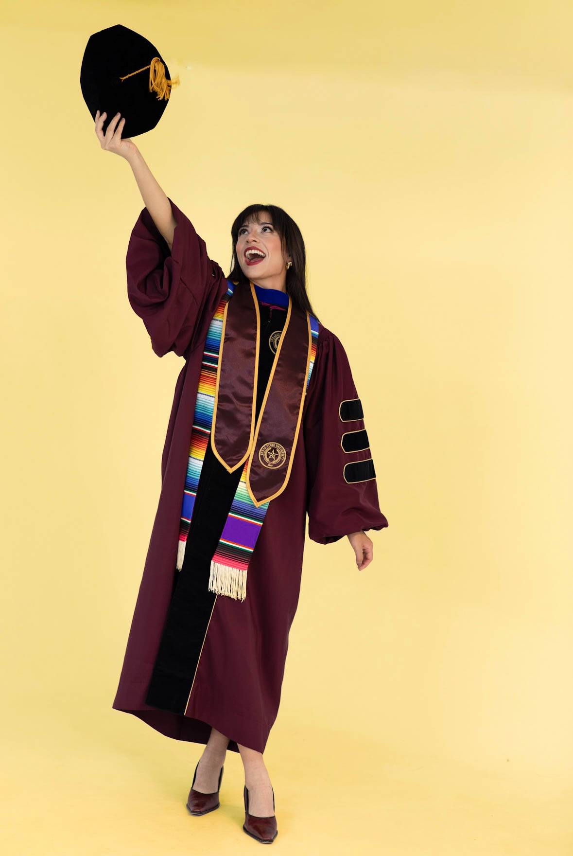 isabella vigil in graduation attire in front of a yellow background