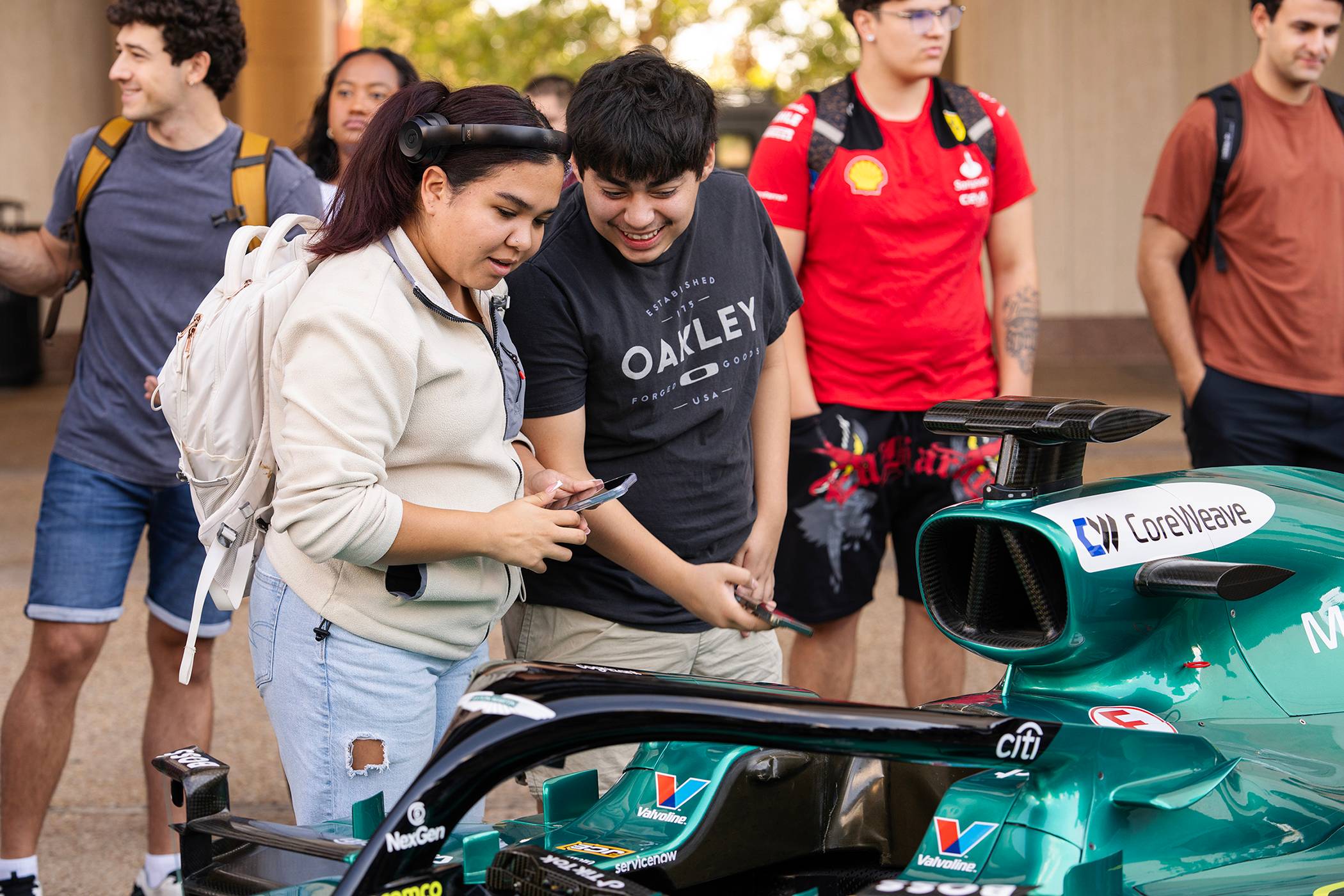 Students excitedly examine details on the Aston Martin Aramco Formula One car.