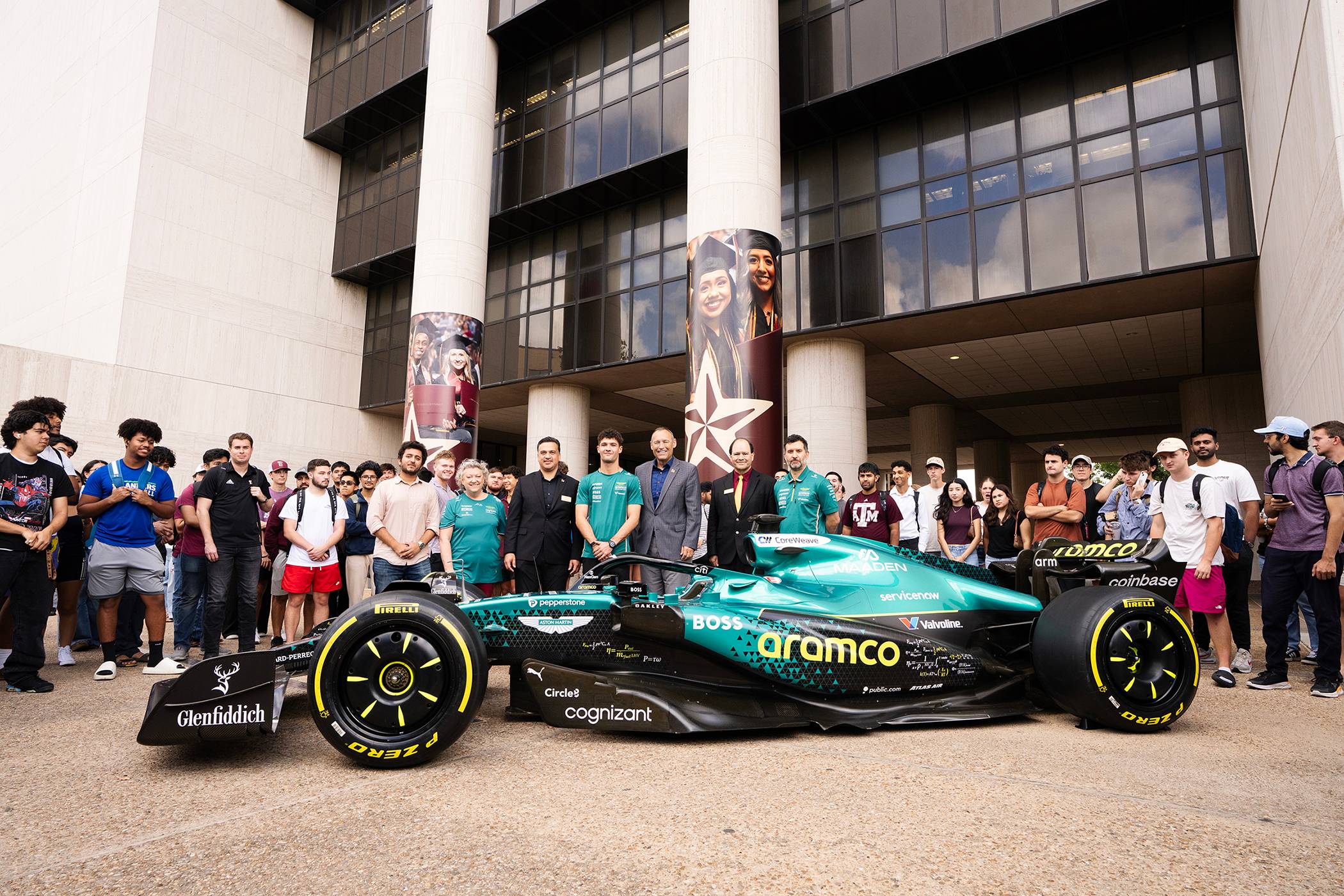Group photo of the Aston Martin Aramco team, TXST students and car in front of Alkek Library.