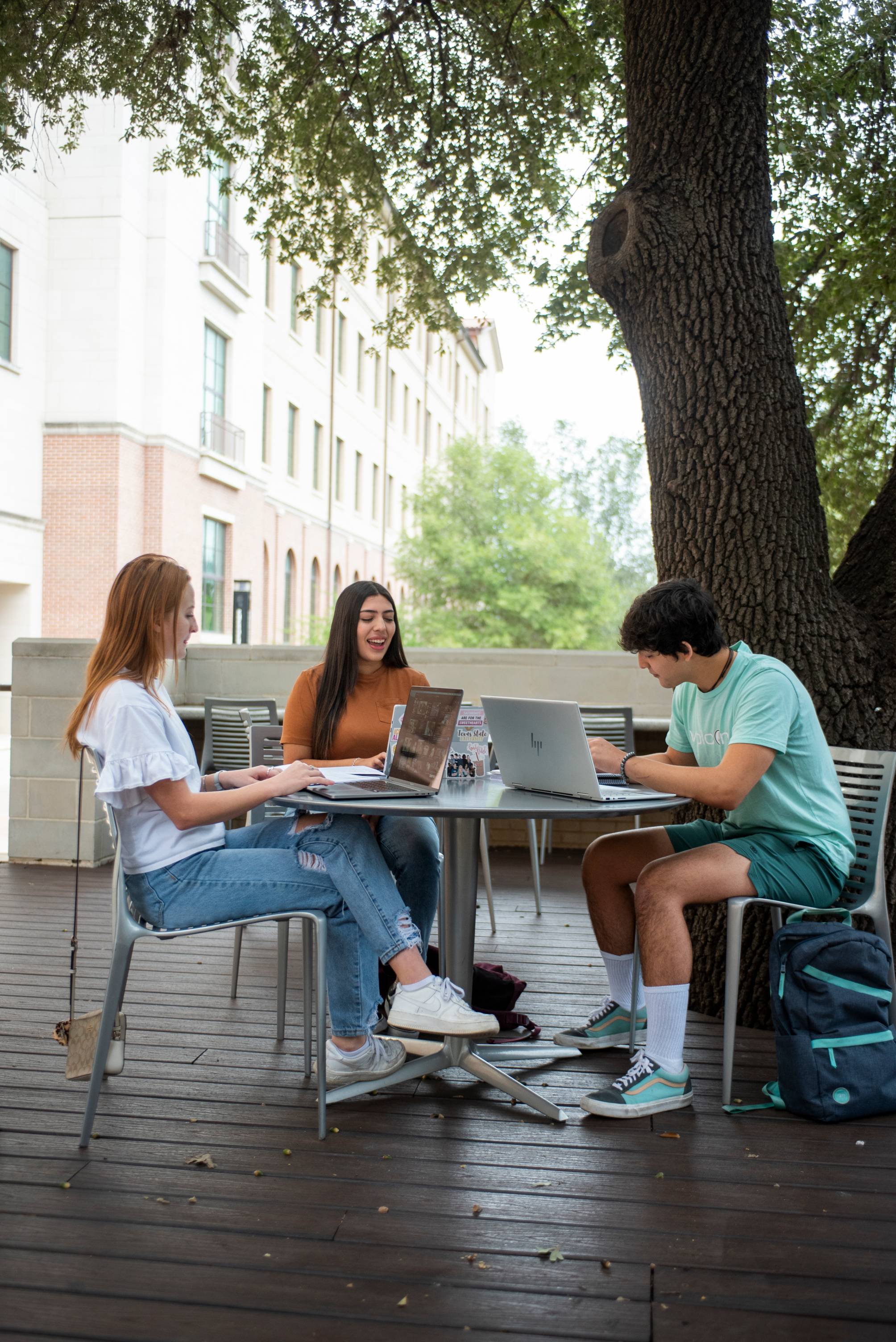 Three students sitting at a table outside of Jones Dining Hall.