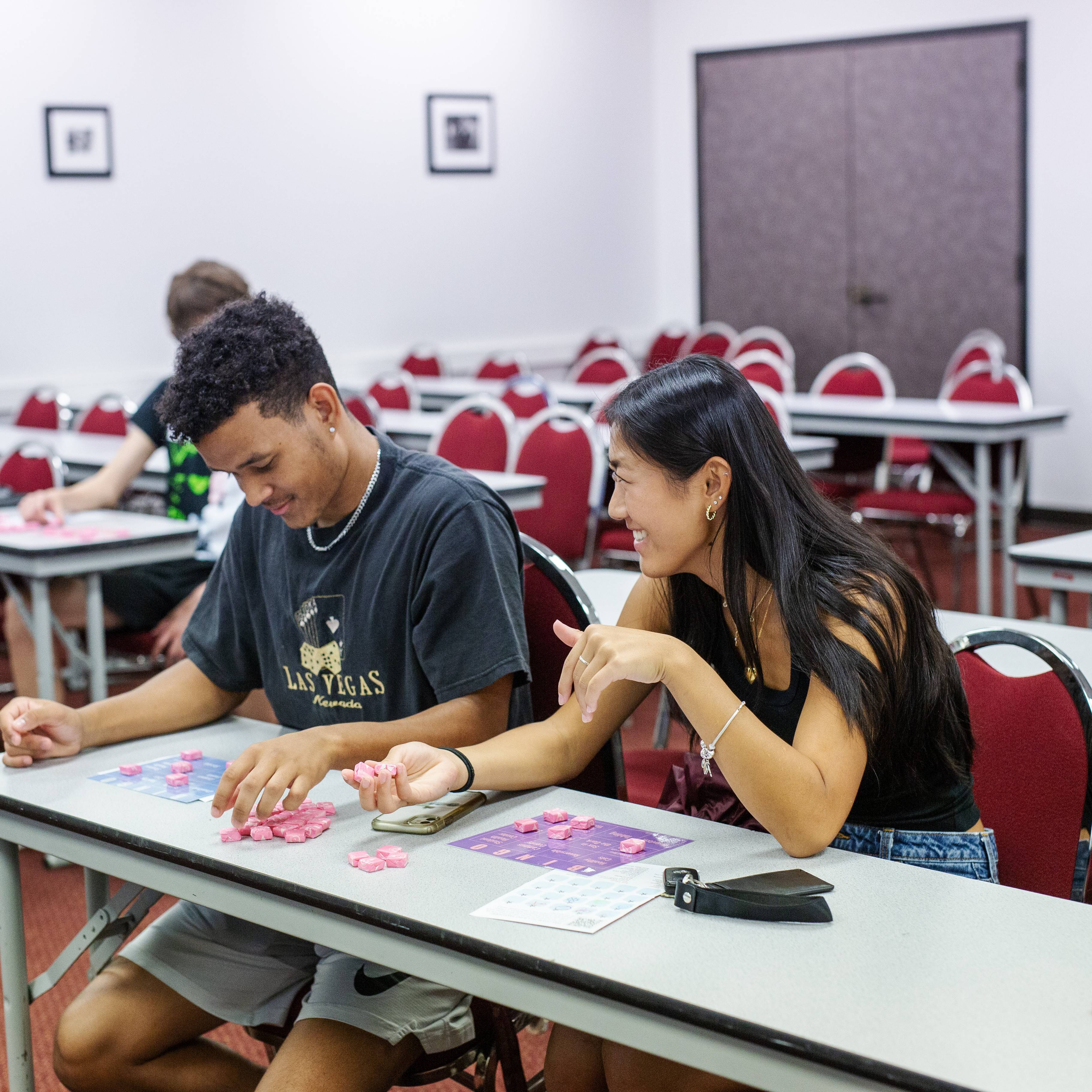 two students sitting at a table playing bingo