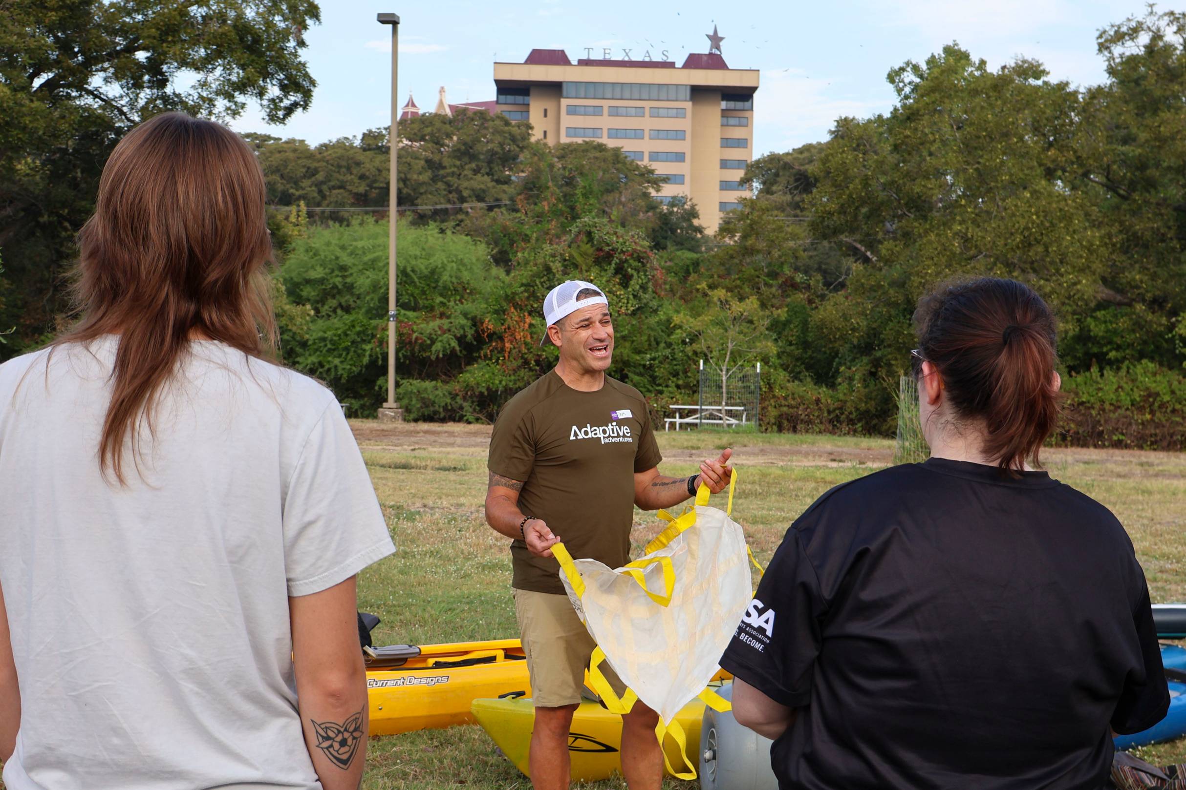 man holds cloth and talks to two young women