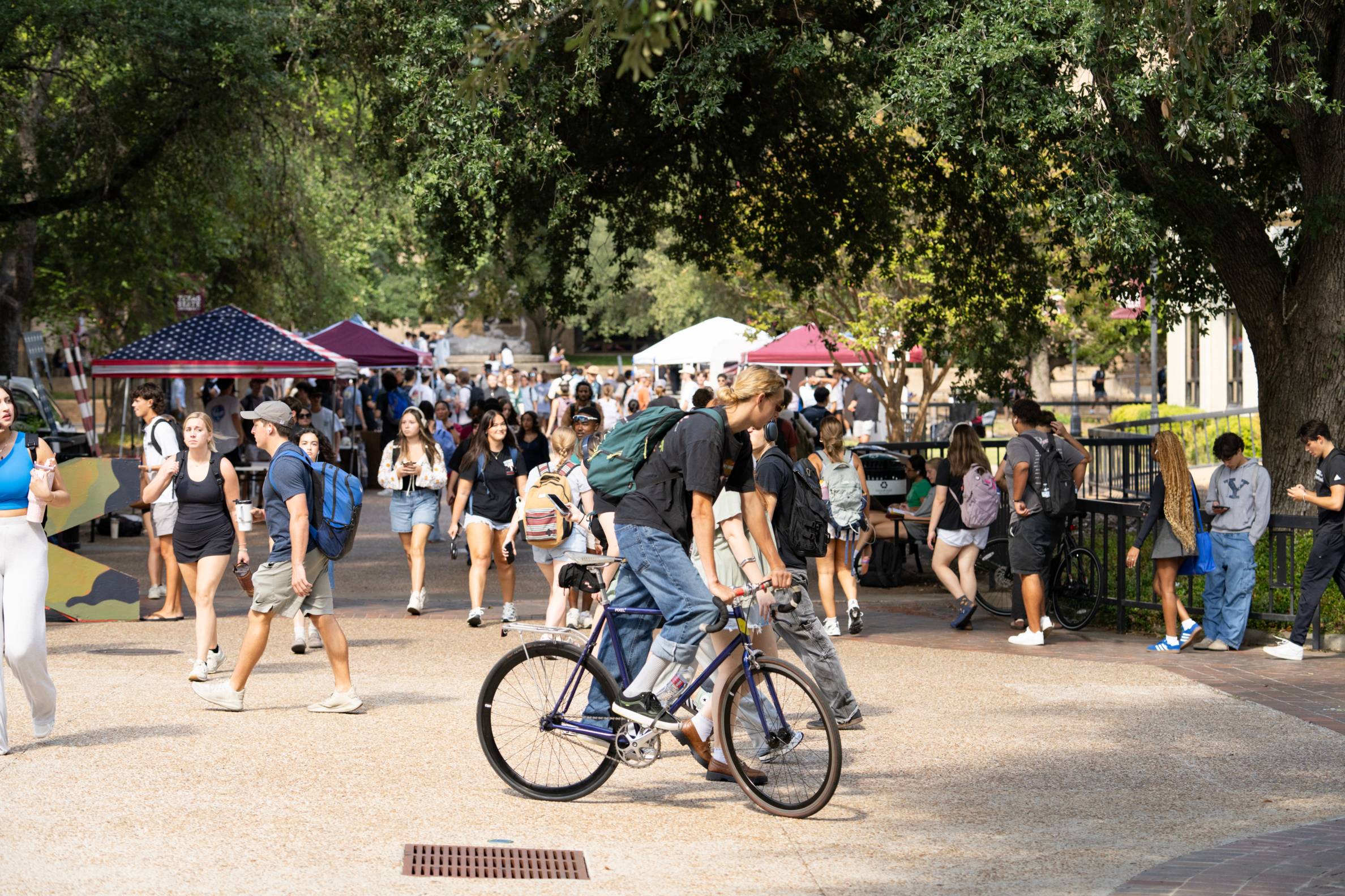 student riding a bike thru the quad