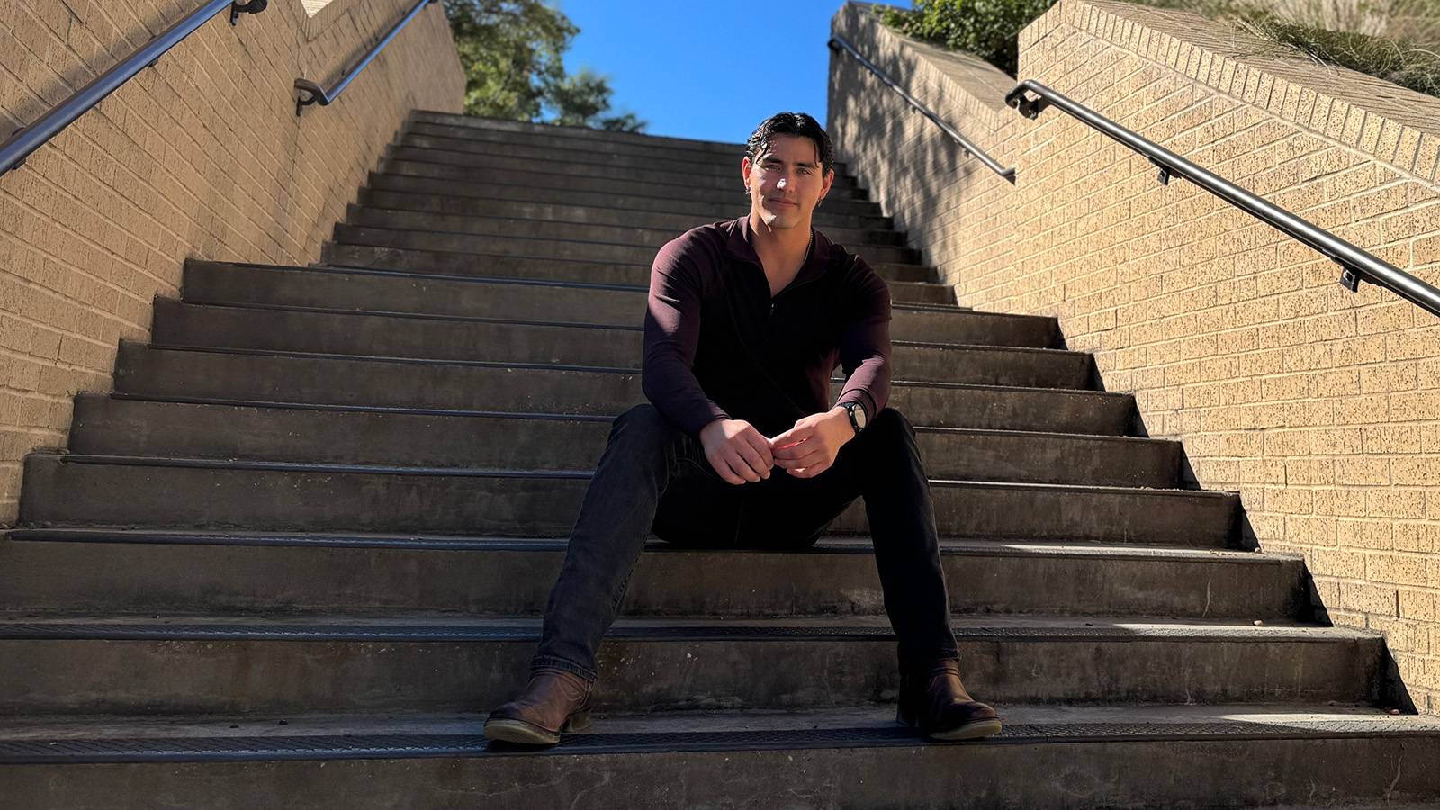 Yeremi Hykel sitting on the steps of McCoy Hall