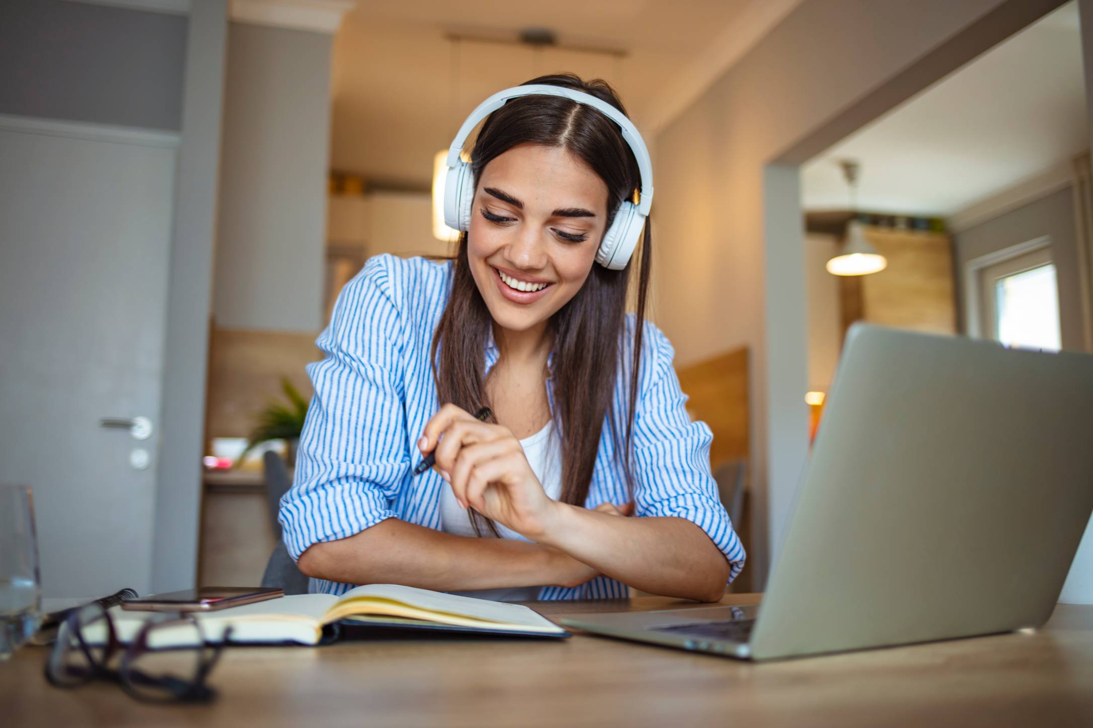 a woman in headphones smiling in front of laptop
