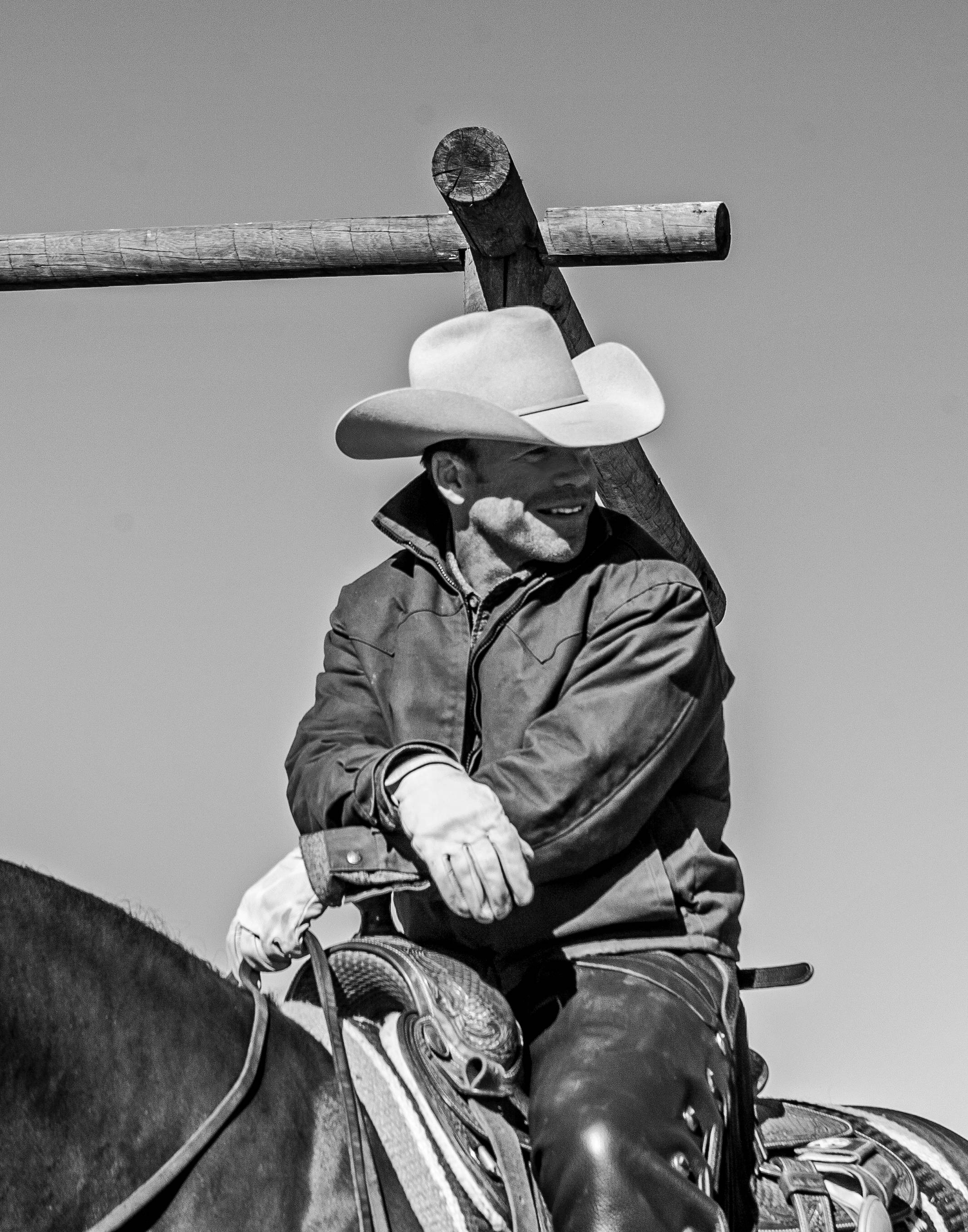 Taylor Sheridan rests his arms on a saddle horn atop a horse