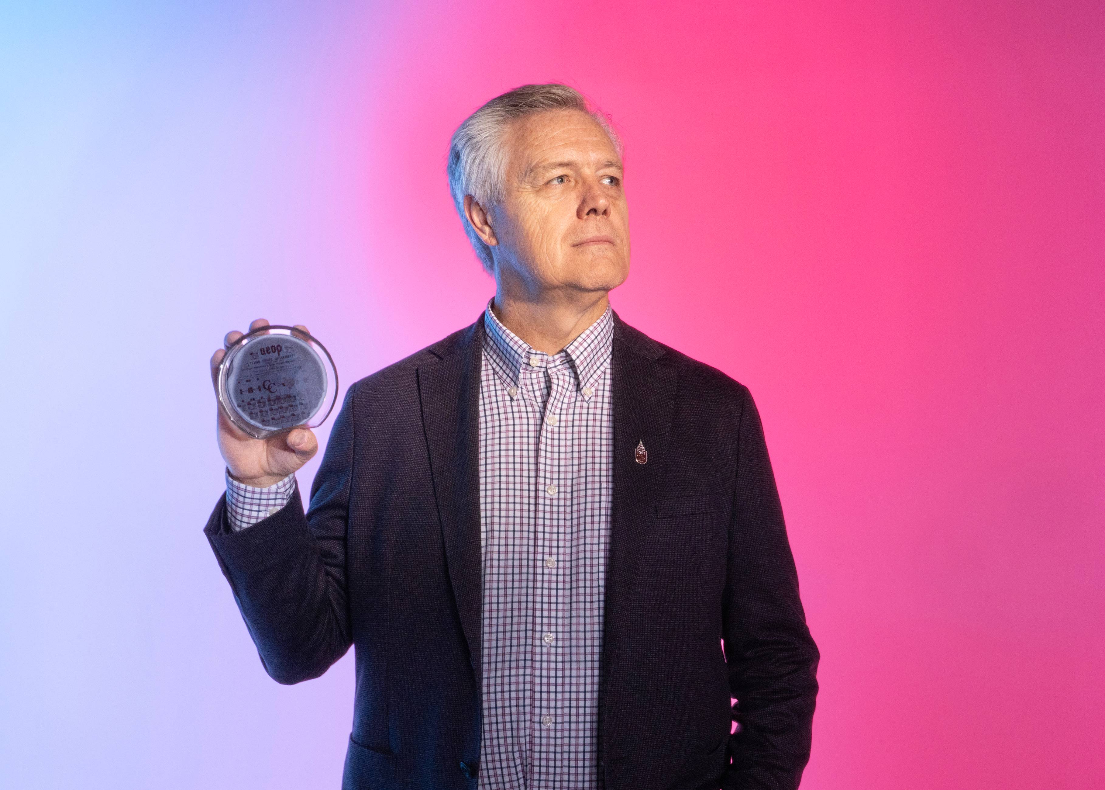 man holding a semiconductor in his right hand as he looks off to his left