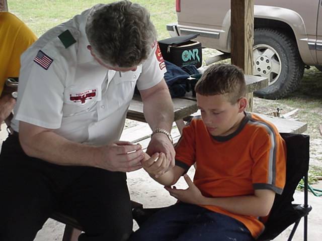 Medical Explorer removing cactus thorns from Boy Scout at camporee first-aid station