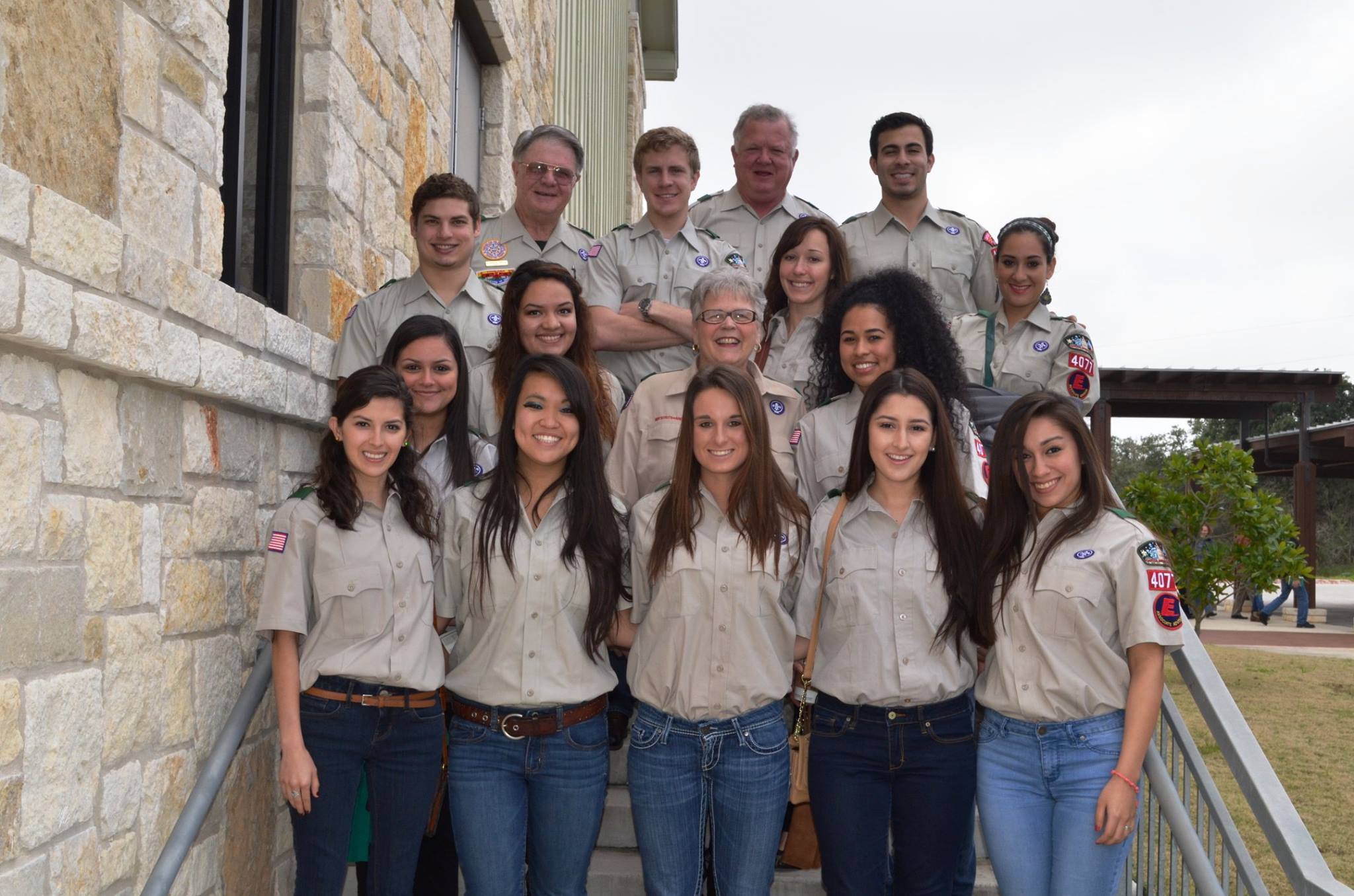 large group of people wearing Scout uniforms while posing for photo while standing on stairs. 