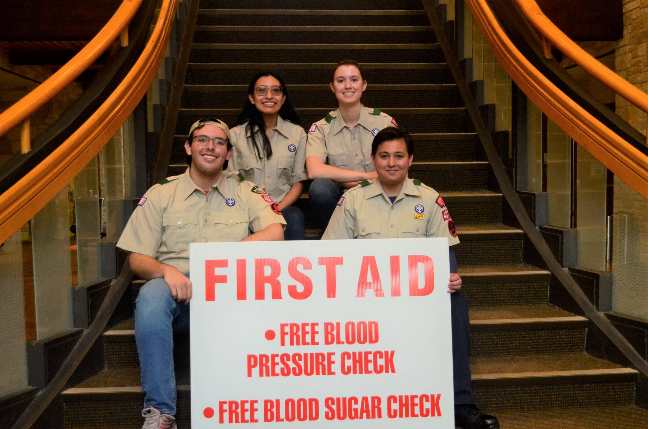 four people in scouting america uniforms holding up a first aid sign