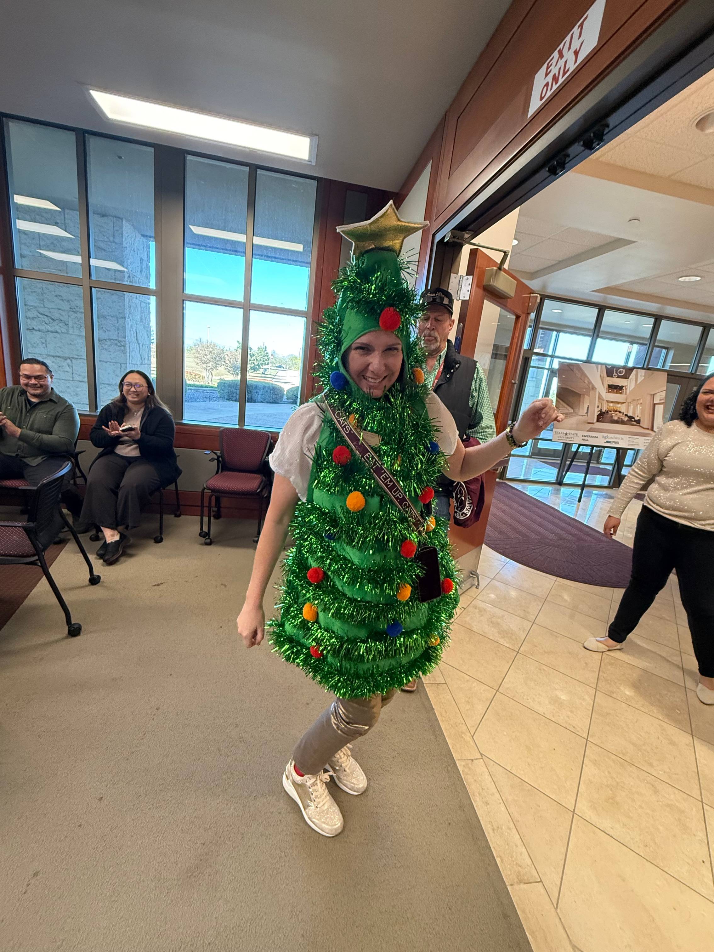 A staff dressed in Xmas tree smiling