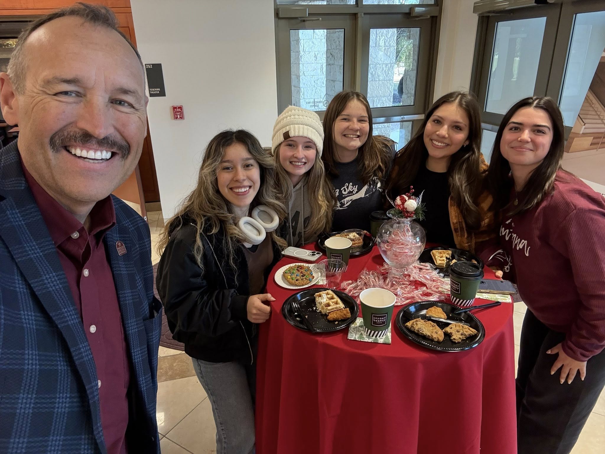 President Kelly Damphousse is taking a selfie with students.