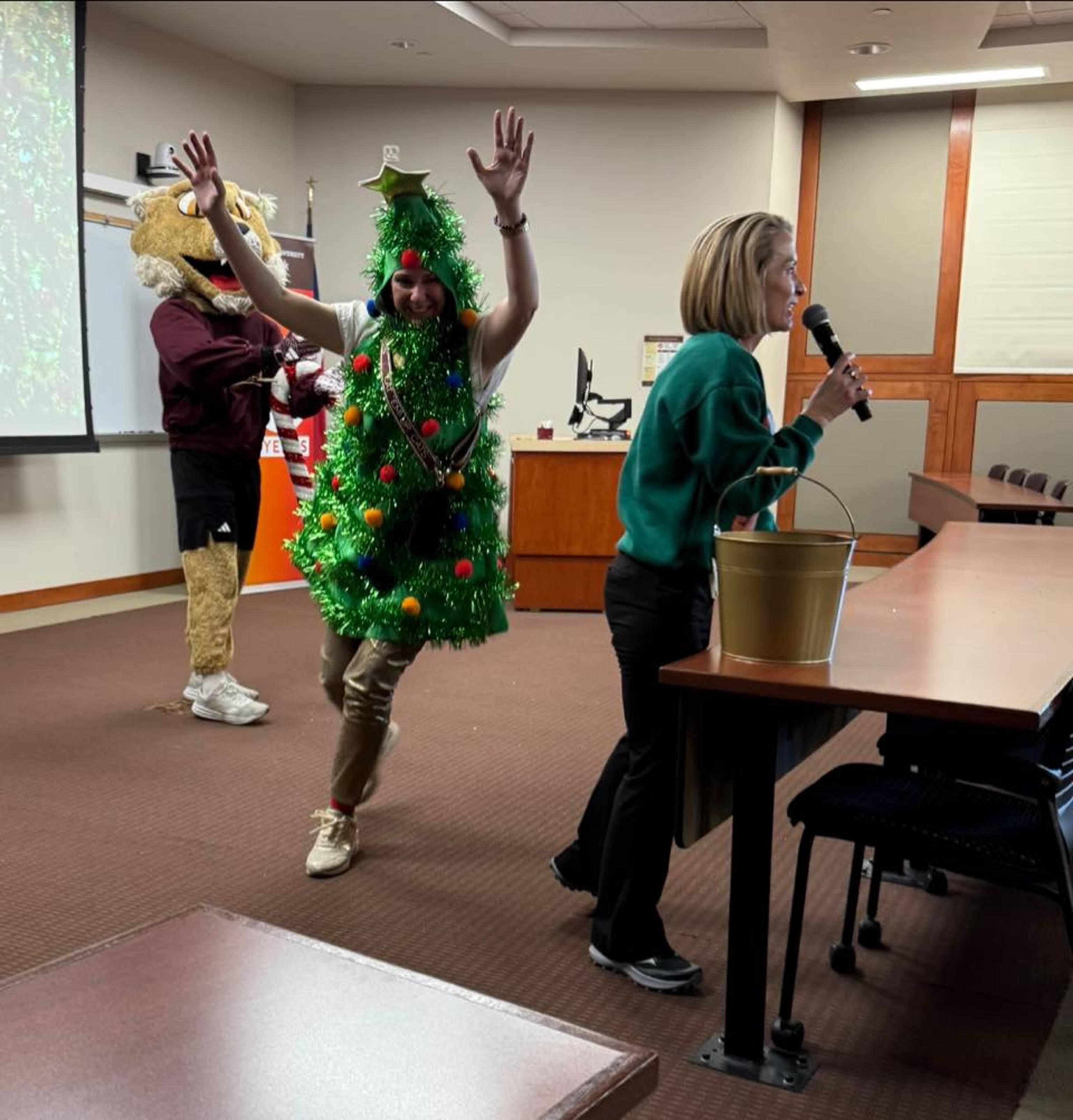 A person wearing a Xmas tree costume cheering everyone up.