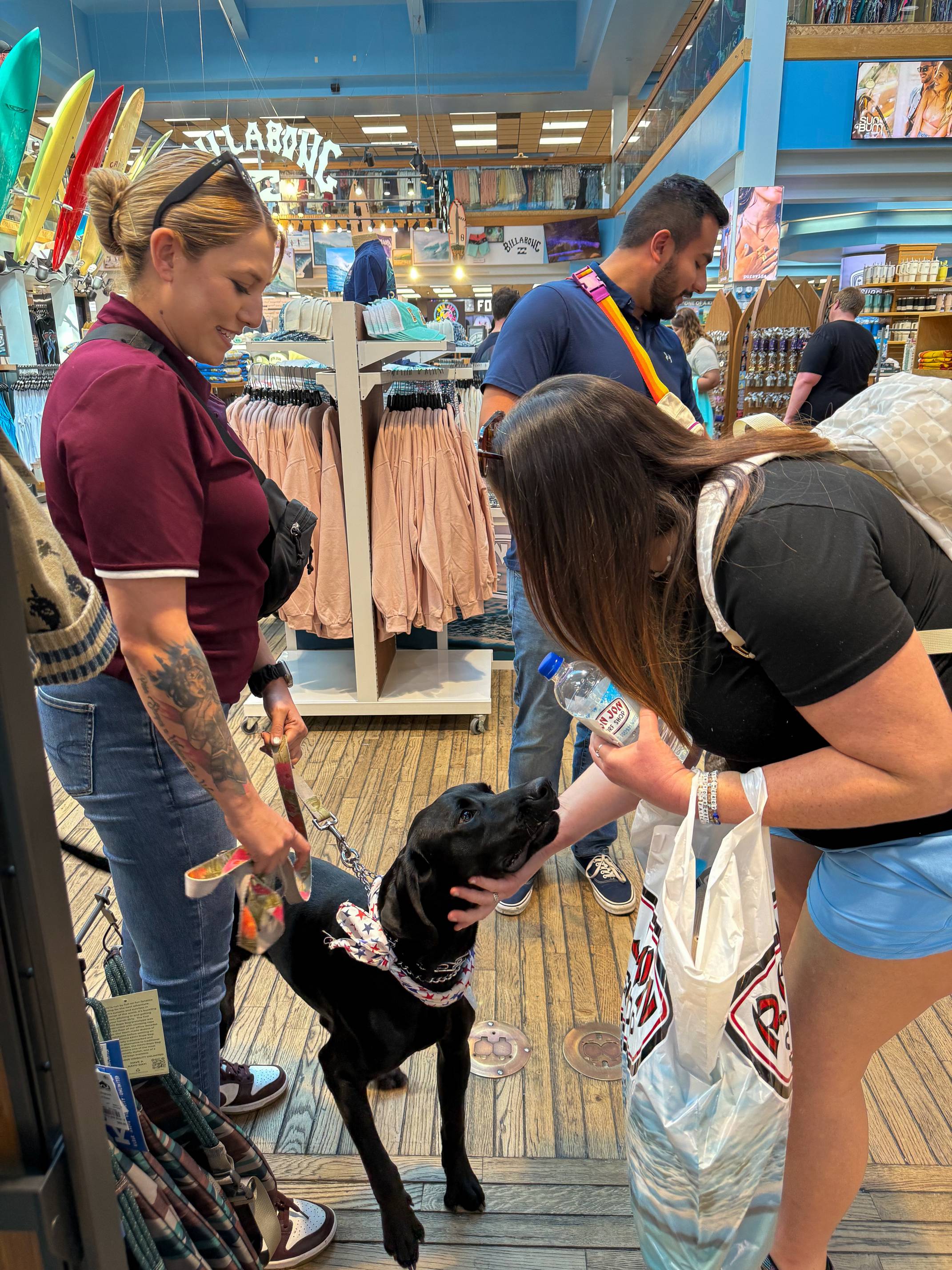 mental health officer and therapy dog interact with a customer in a crowded store