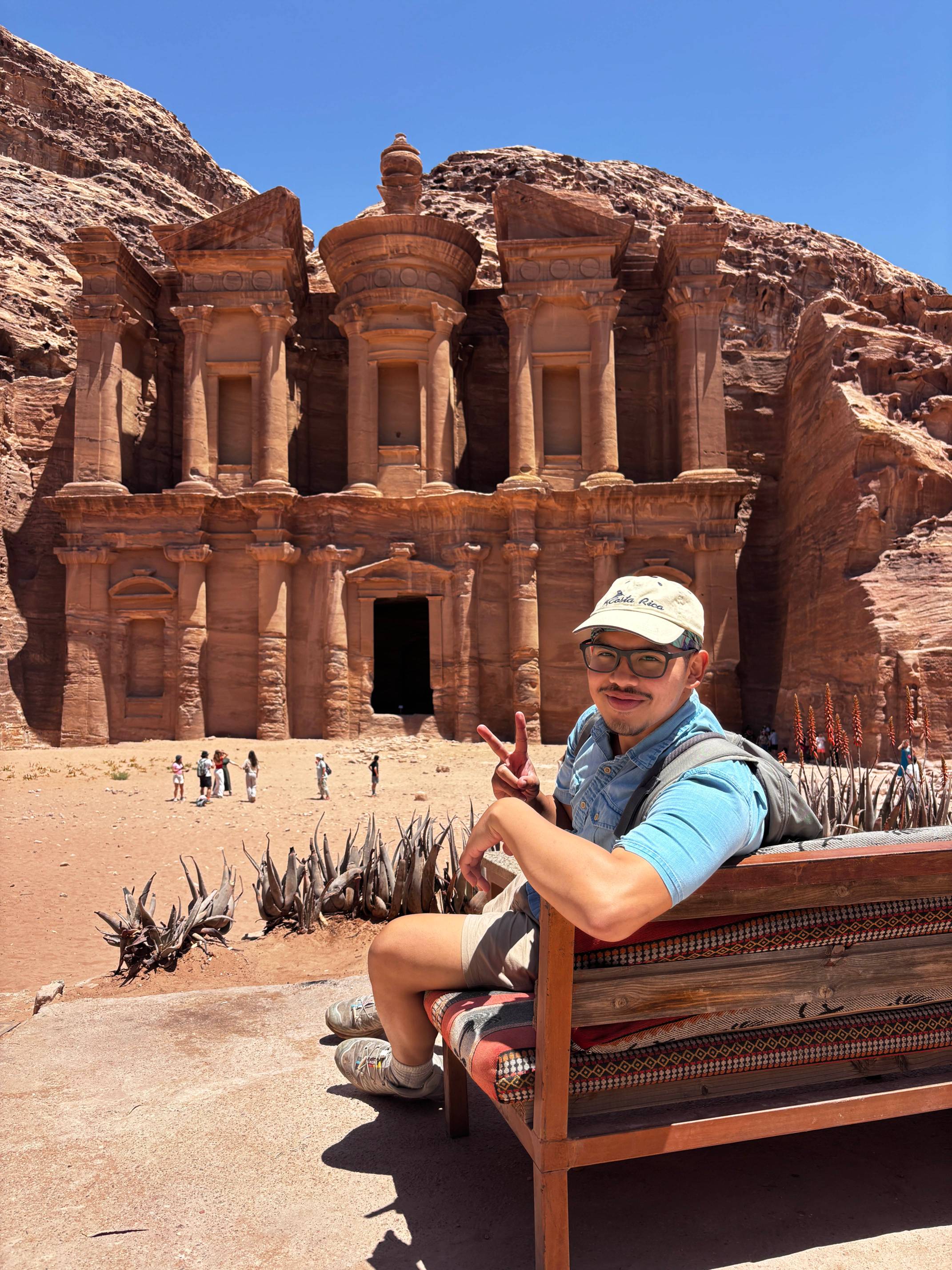 man holding up the peace sign in front of landmark in Jordan
