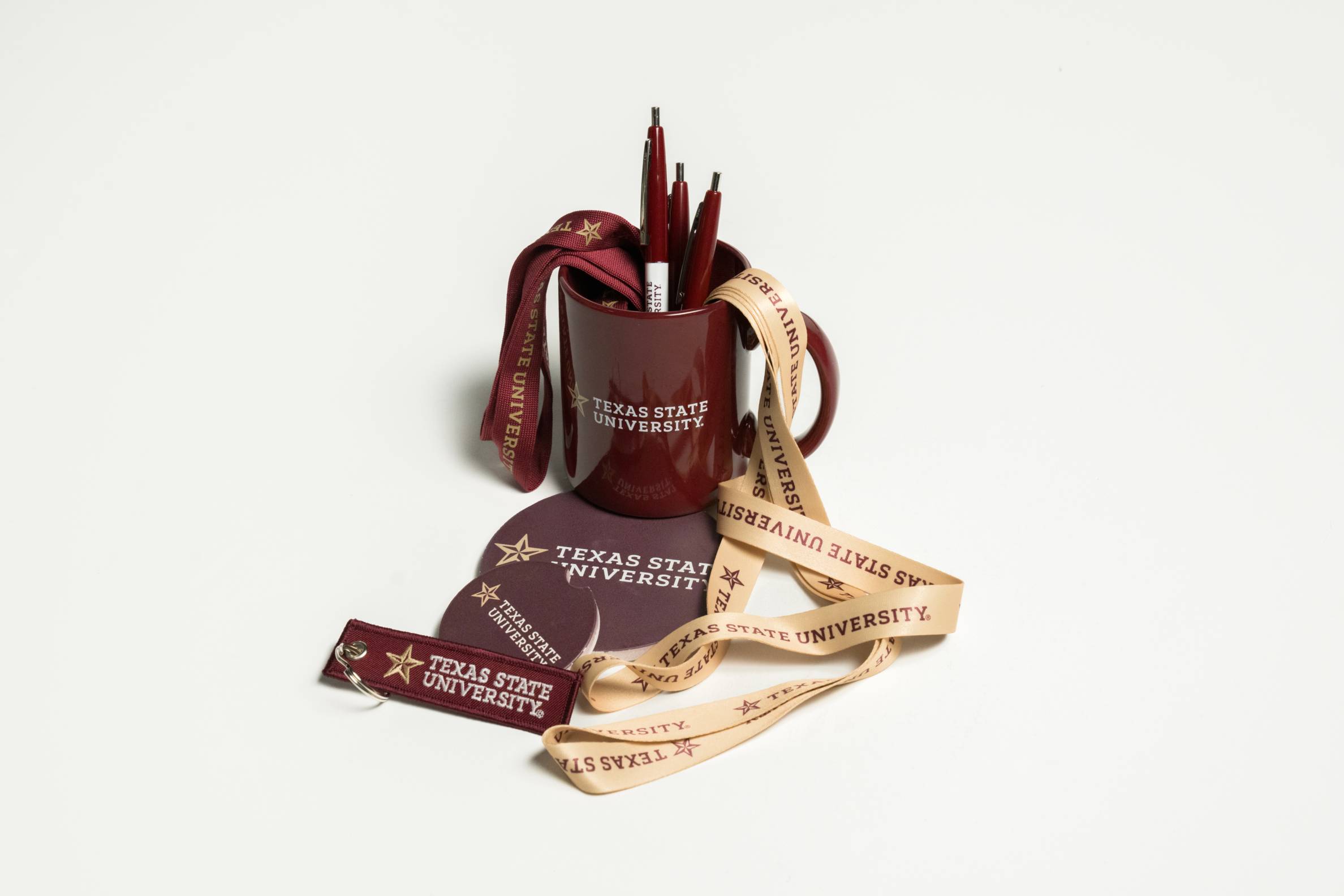 Cluster of pens, lanyards, coasters, and other objects emblazoned with Texas State branding