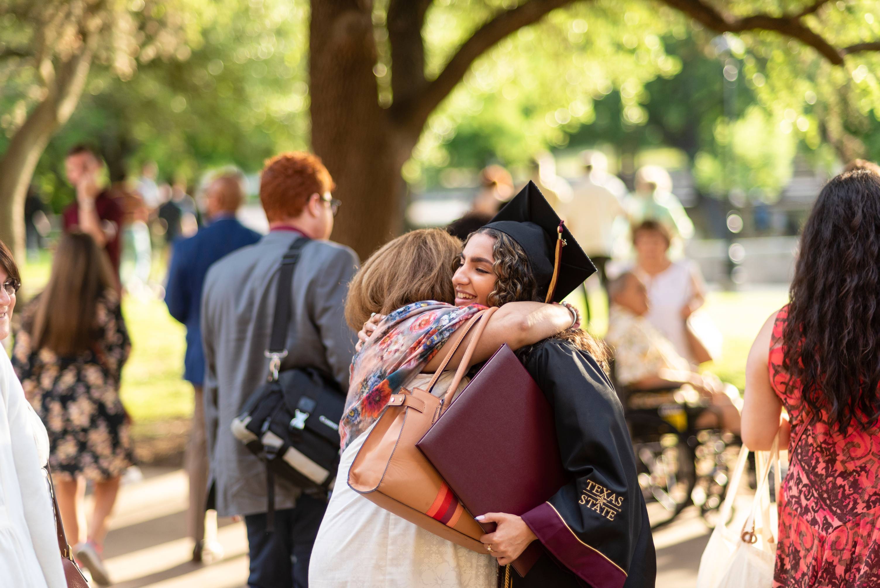 family members hugging at TXST graduation