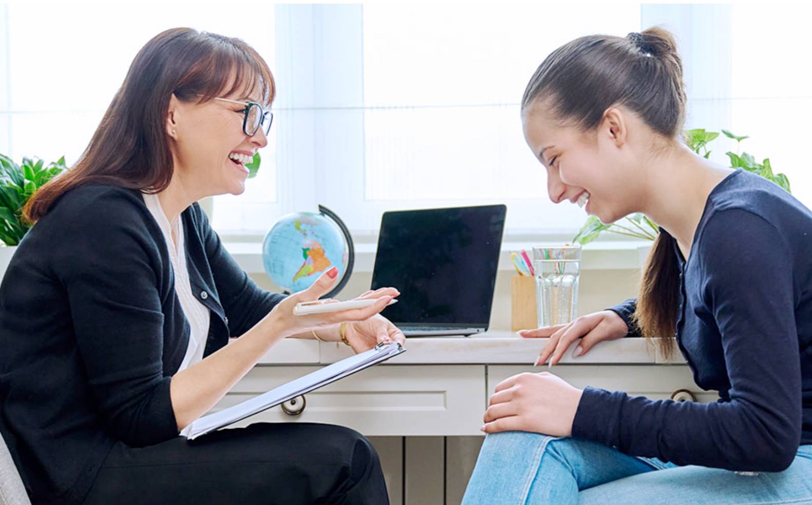 two women talking by a laptop