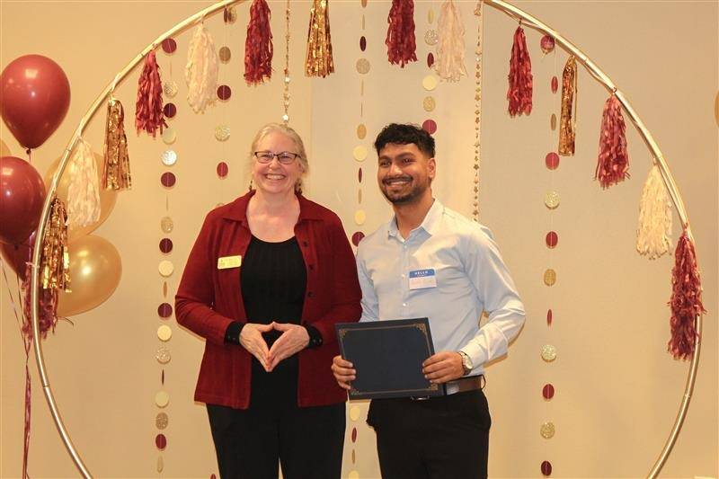 library directory handing out certificates to a third place winner team Rijal