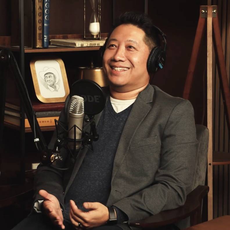 man smiling sitting behind a microphone