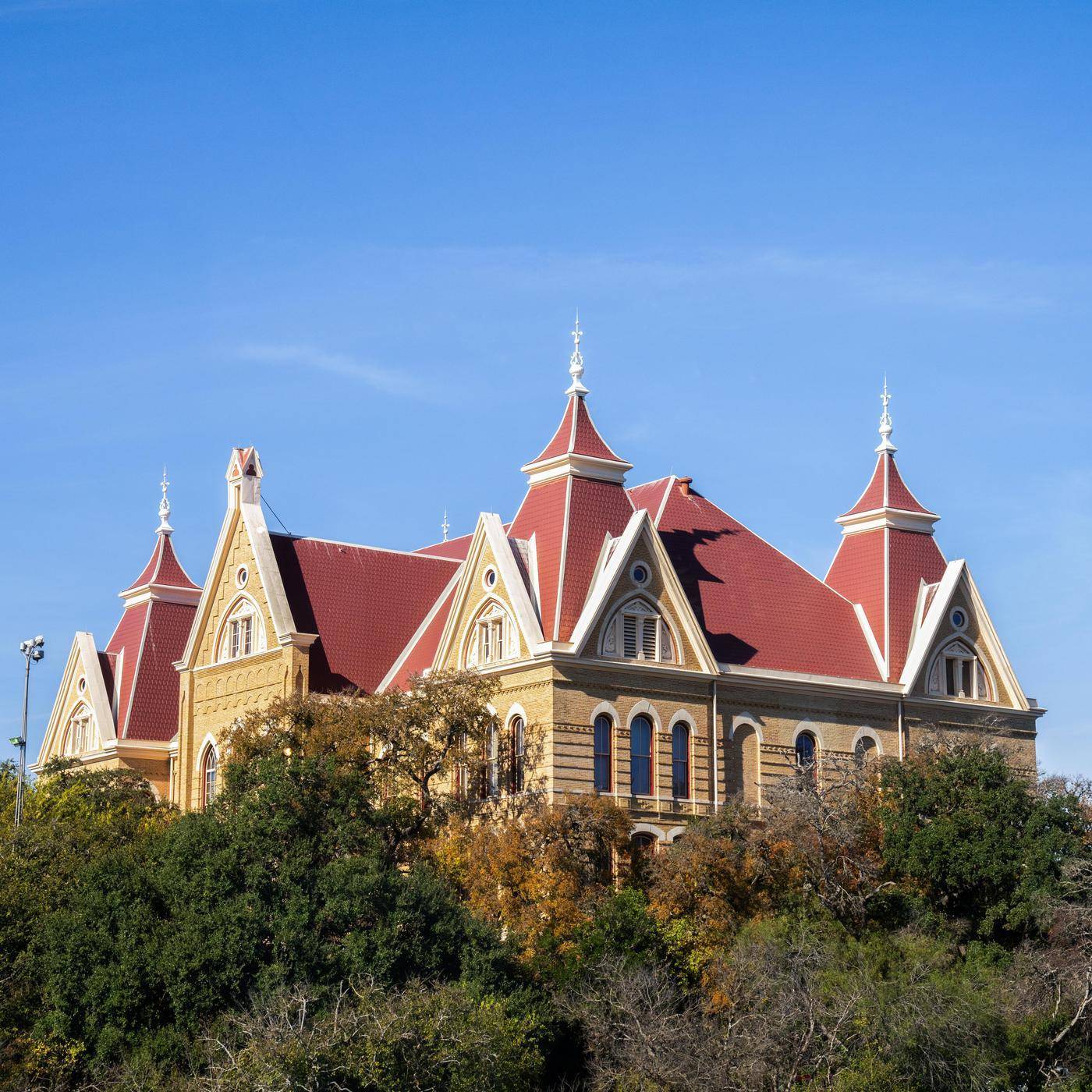 Old Main peeks above the tree tops on a bright, clear day.