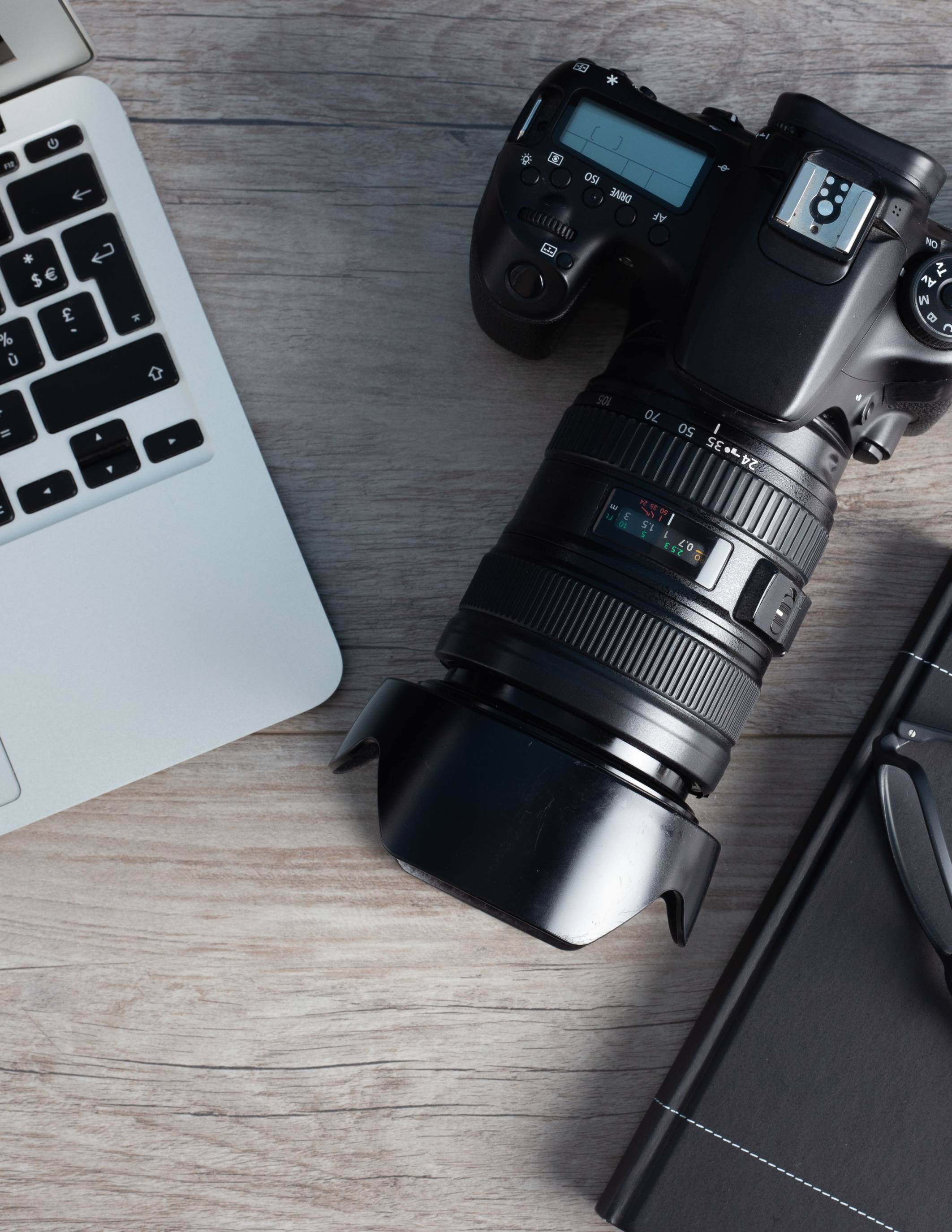 a laptop, digital camera and notebook laying on desk