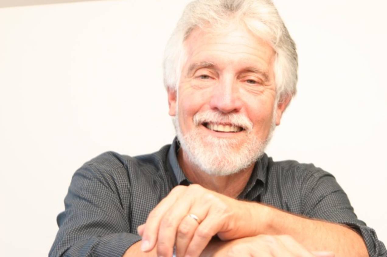 a smiling man with grey hair and beard