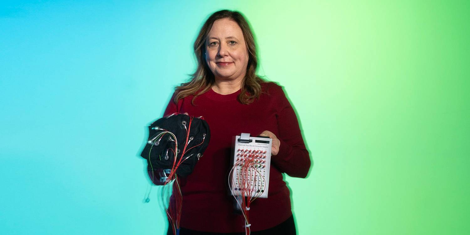 Dr. Carmen Westerberg holding medical devices in front of a blue and green gradient background.