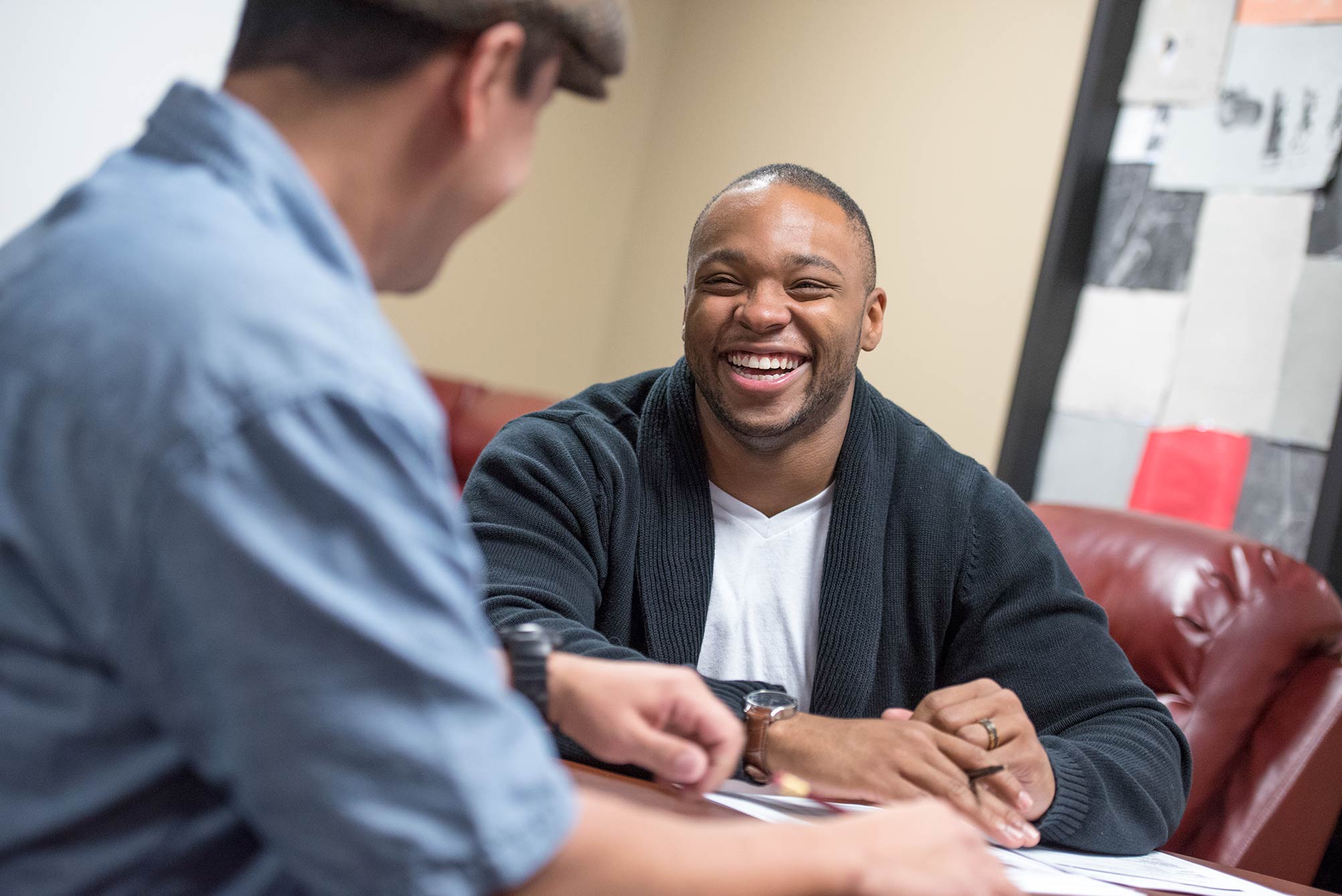 a veteran student laughs while chatting with another student