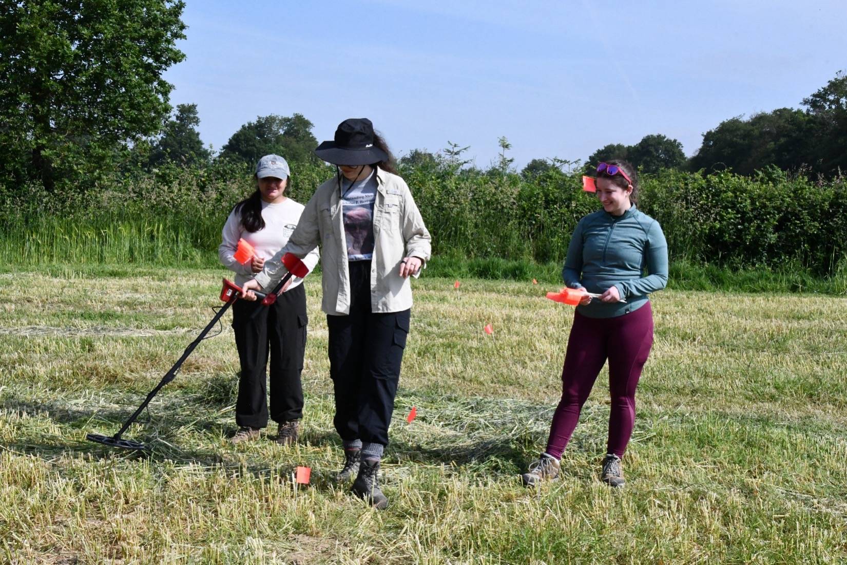 researchers in a field using metal detectors