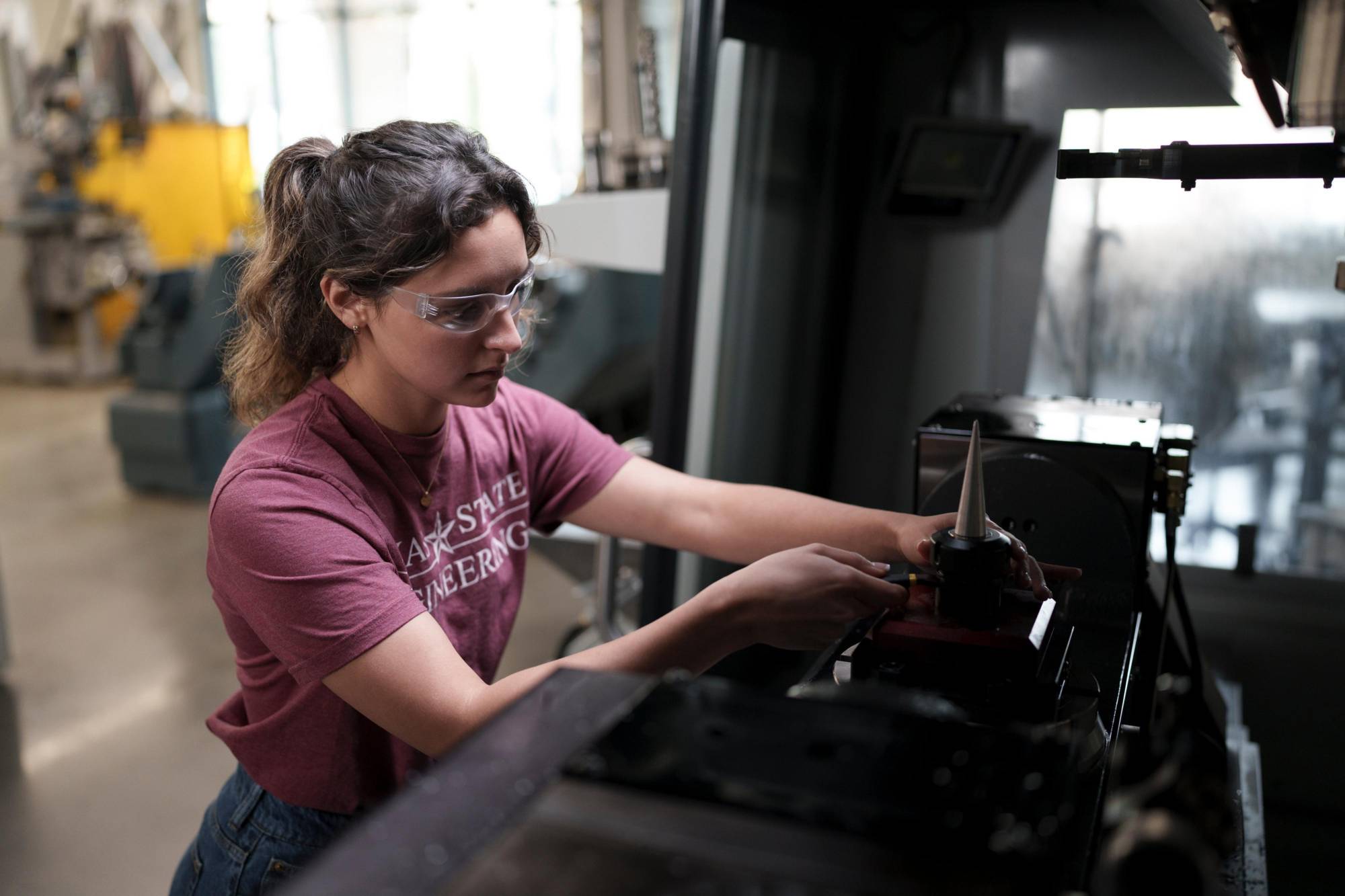 woman in TXST engineering shirt working on mechanical system