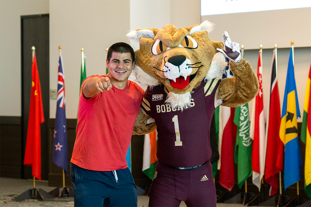student posing with TXST mascot Boko at an event for international scholars