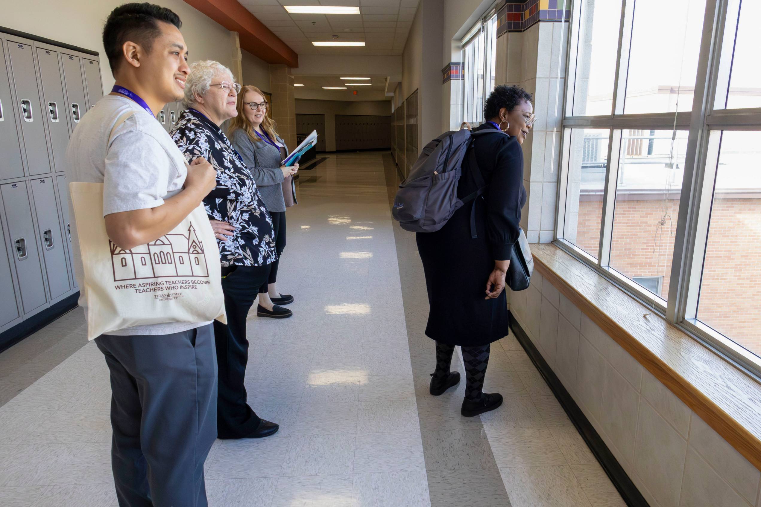 a young man and three women look outside of a window