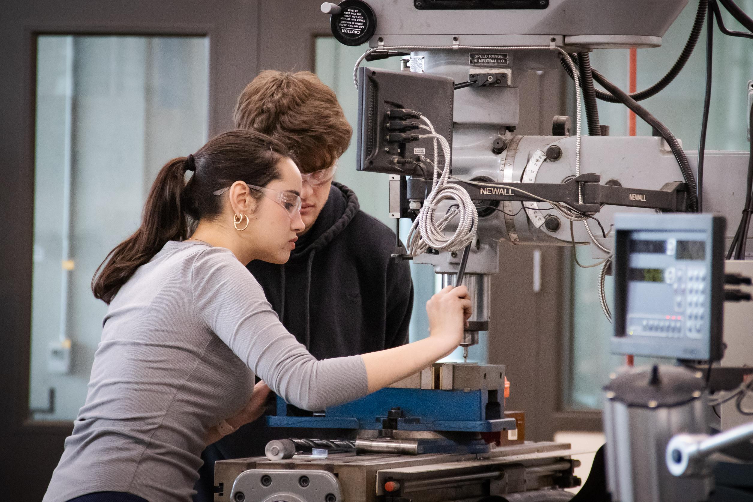 Students using manual mill in industrial makerspace