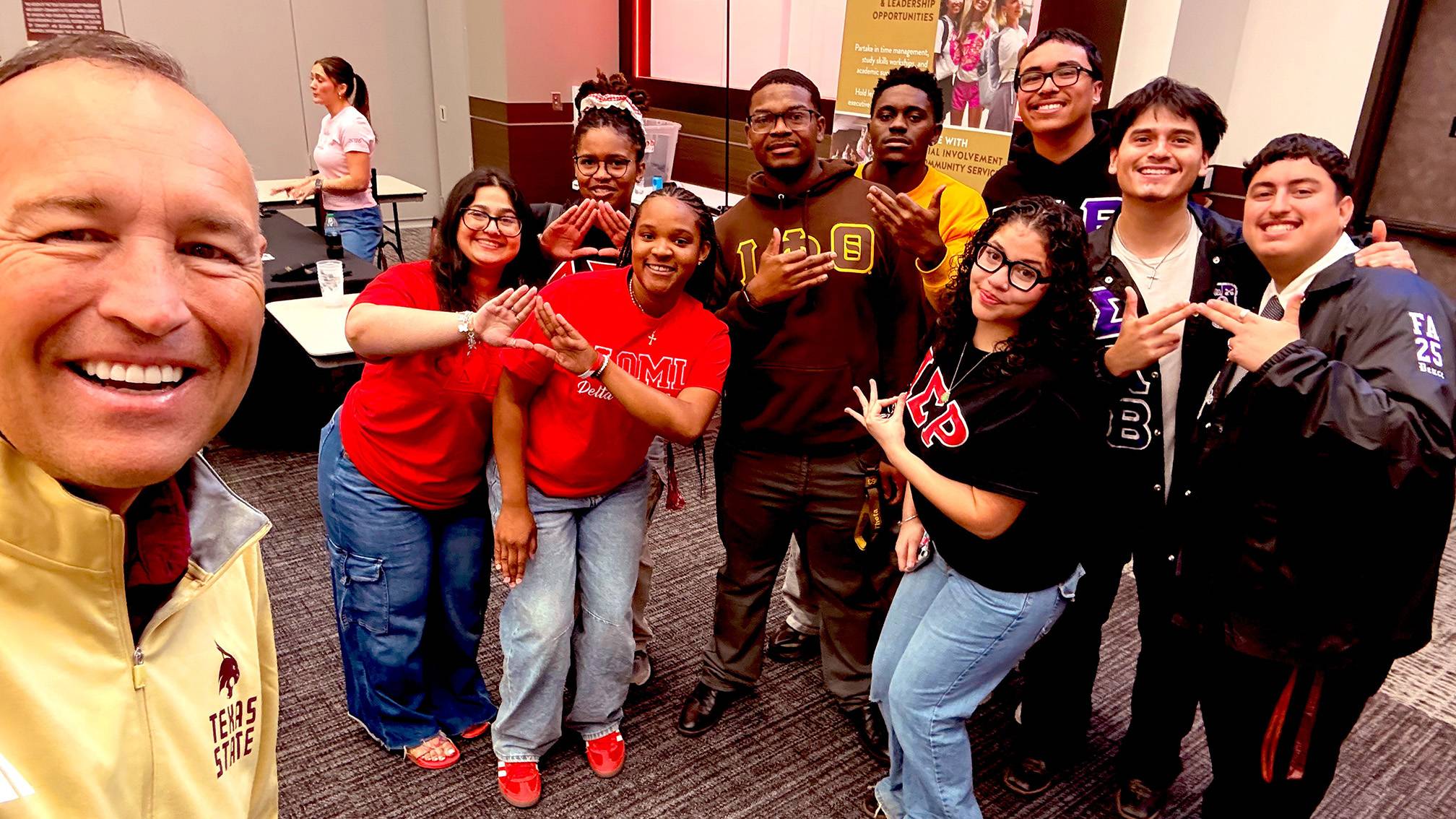 President Damphousse (left) poses for a photo with a group of students.