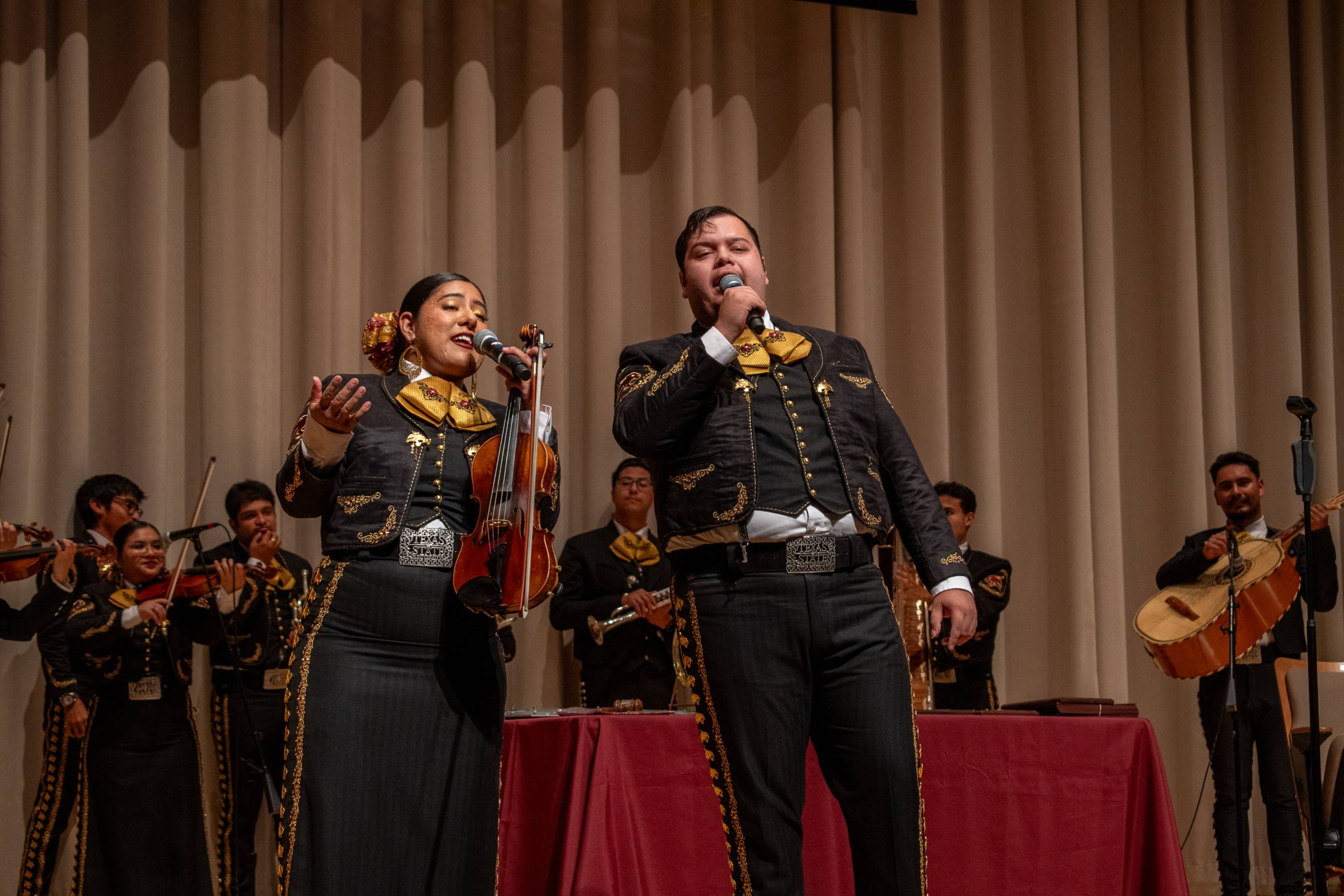 A photo of two mariachis singing at the performing arts center