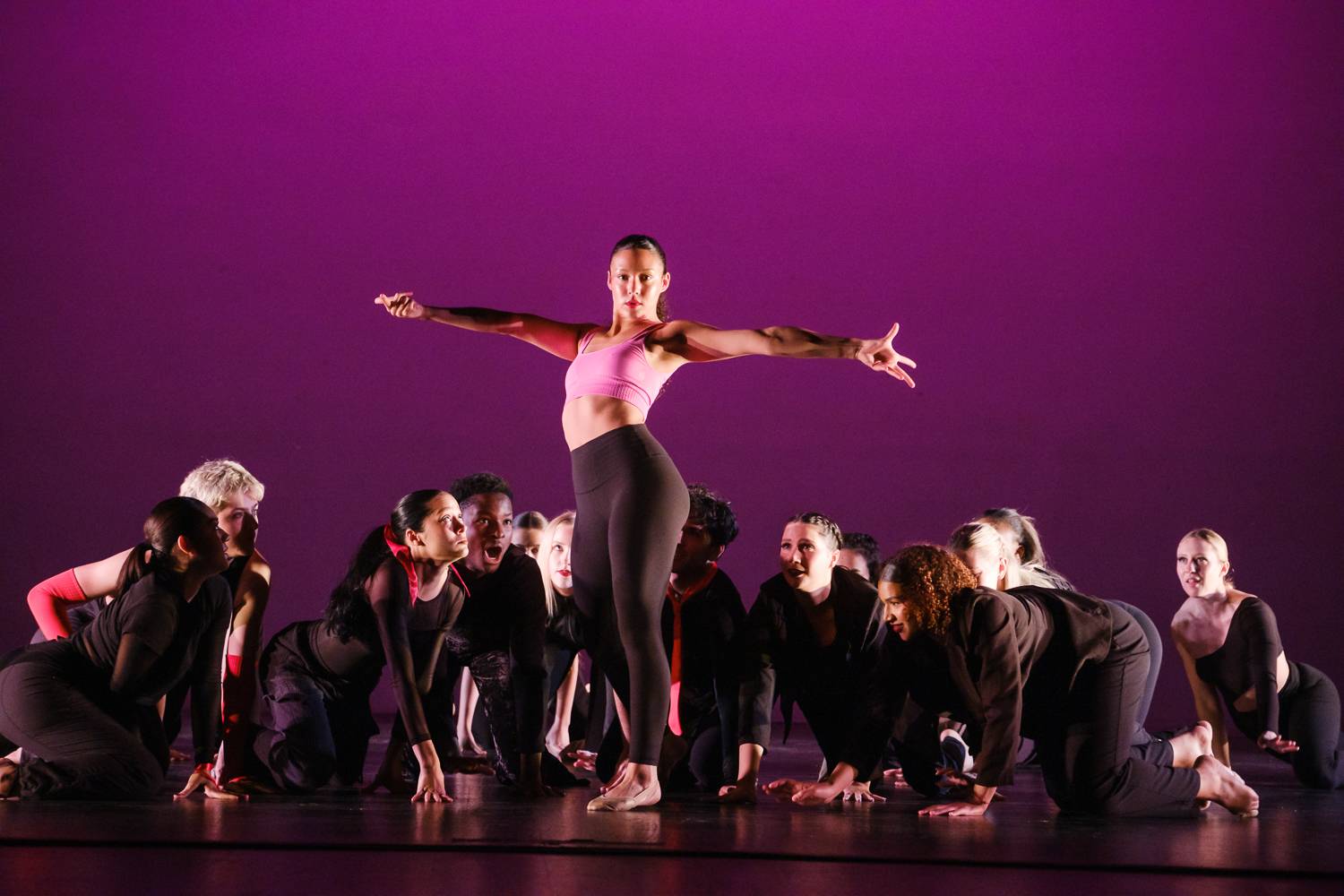 Students dancing on stage. A main performer is showcased with students below her. 