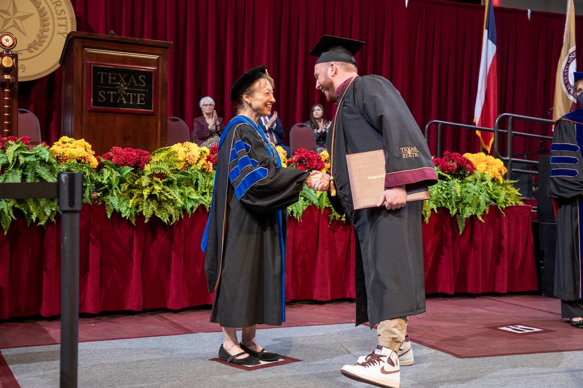 Dr. Trauth shaking hands with a student at commencement