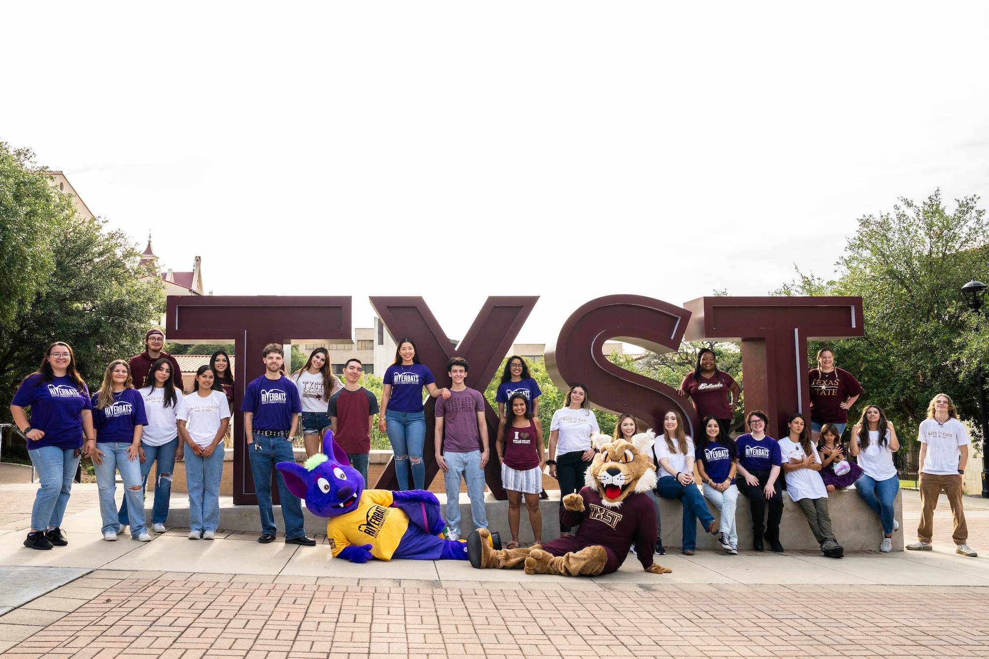 Texas State and Austin Community College students and mascots in front of TXST sign