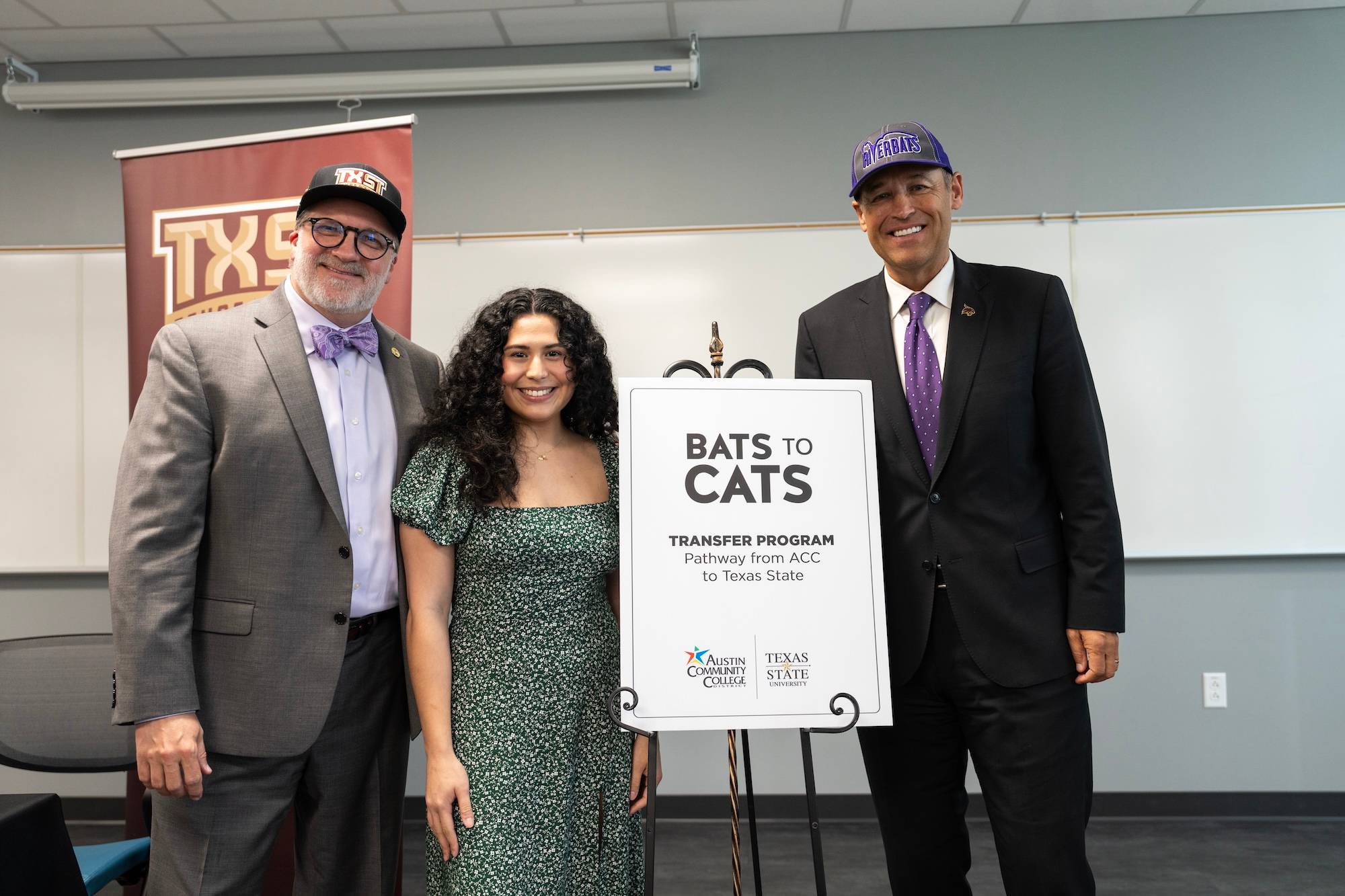 Austin Community College chancellor, a transfer student, and President Kelly Damphousse in front of Bats to Cats sign
