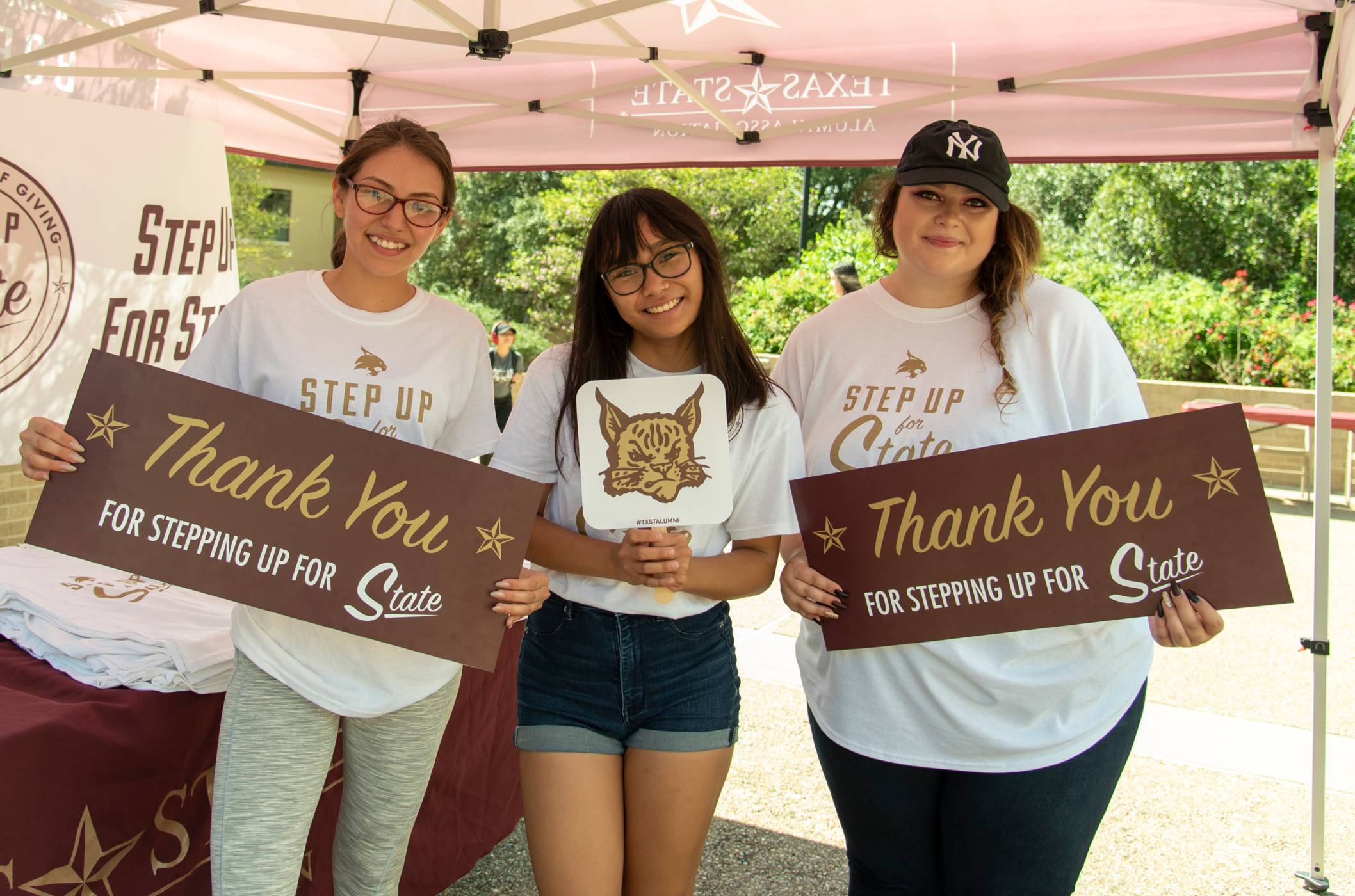 three women holding up signs that read "thank you for stepping up for state"