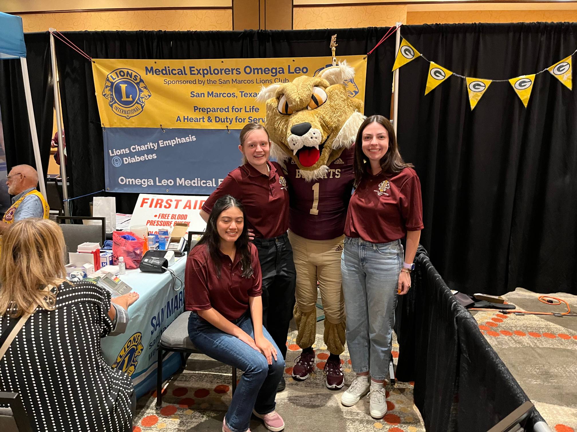 three women pose for photo with bobcat mascot